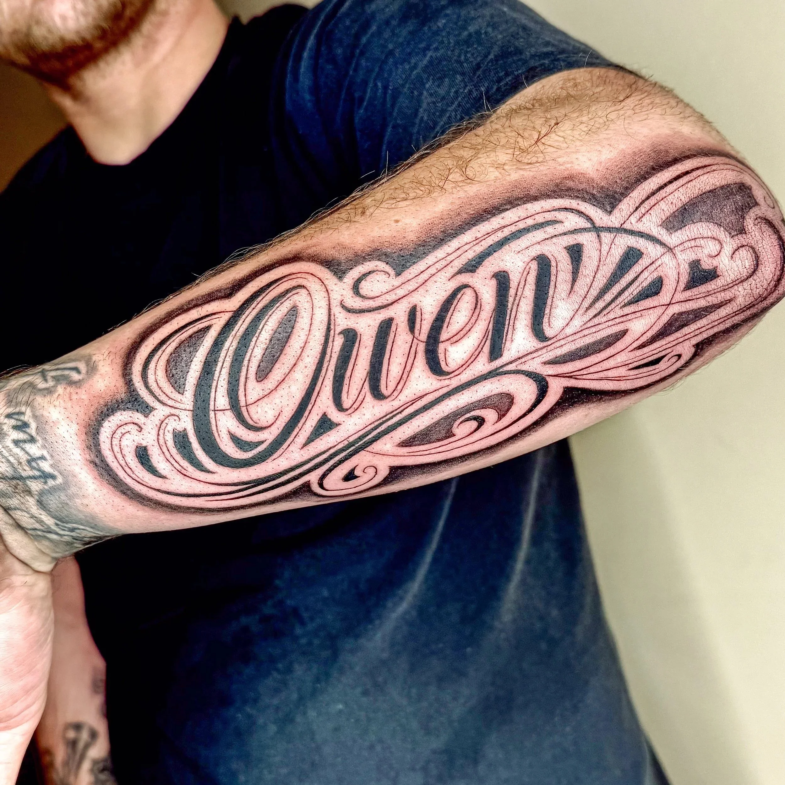 Close-up of a person's arm with a tattoo of the word 'Love' in elaborate script.