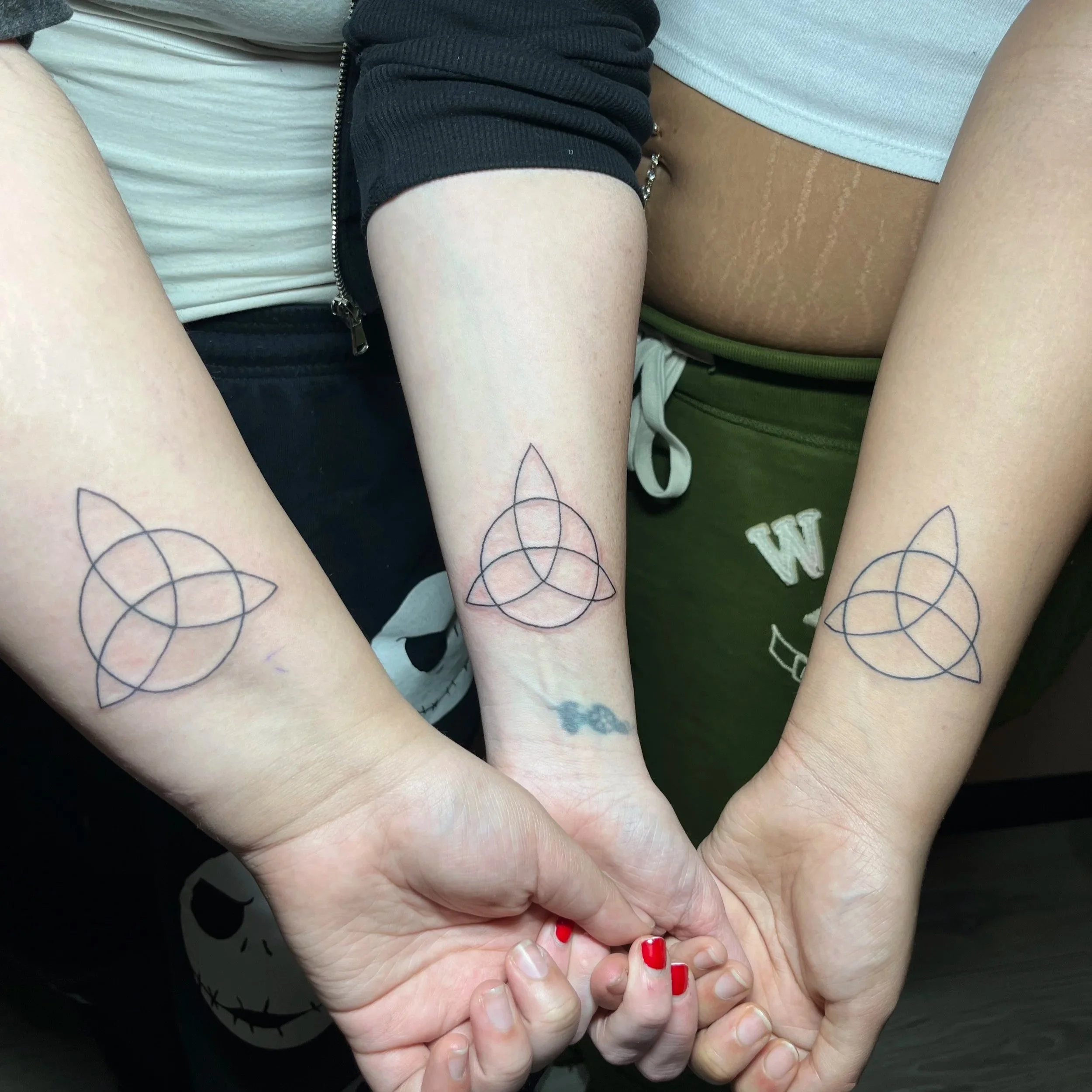 Close-up of two people holding hands with visible tattoos on their arms.