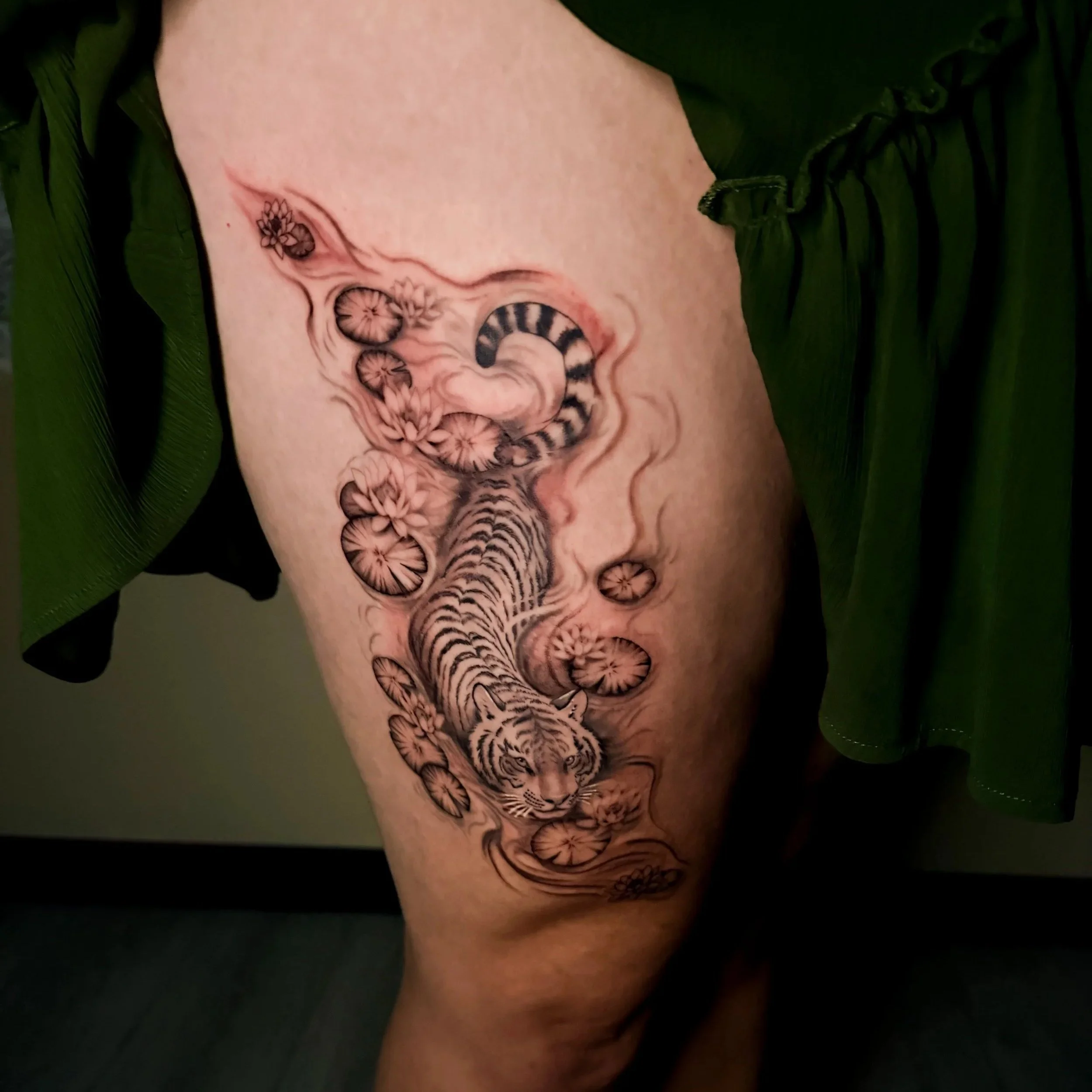 Close-up of a person's thigh with a detailed black and gray tiger face tattoo 