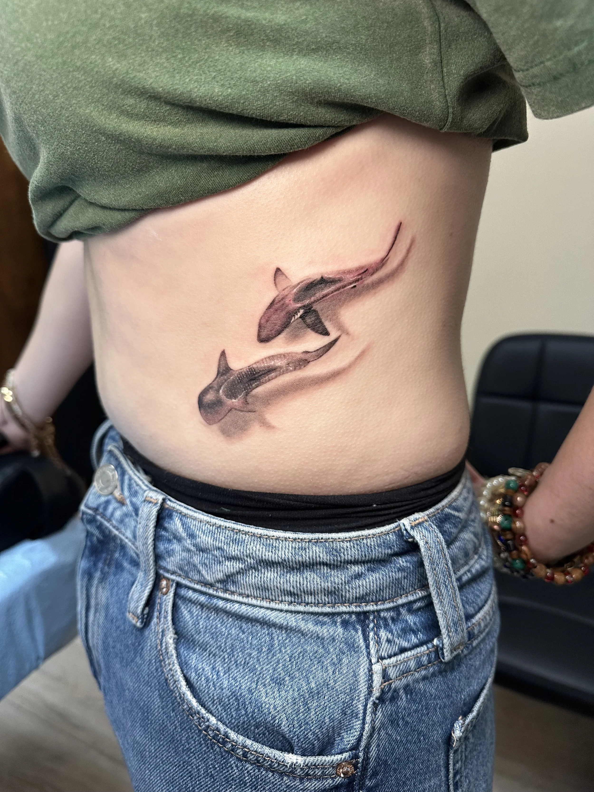 Tattoo of two koi fish on person's side, with one fish swimming upward and the other downward.