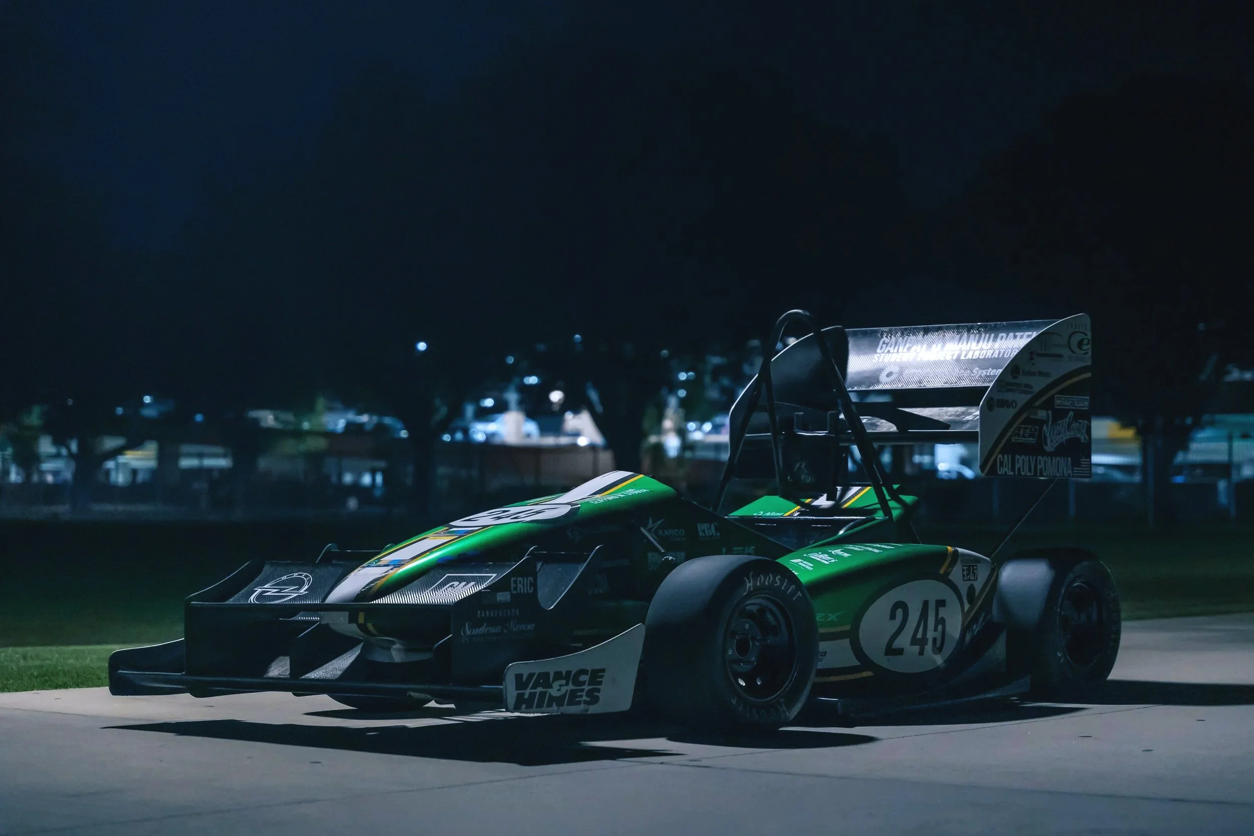 Race car with the number 245 on the side parked on a track at night.