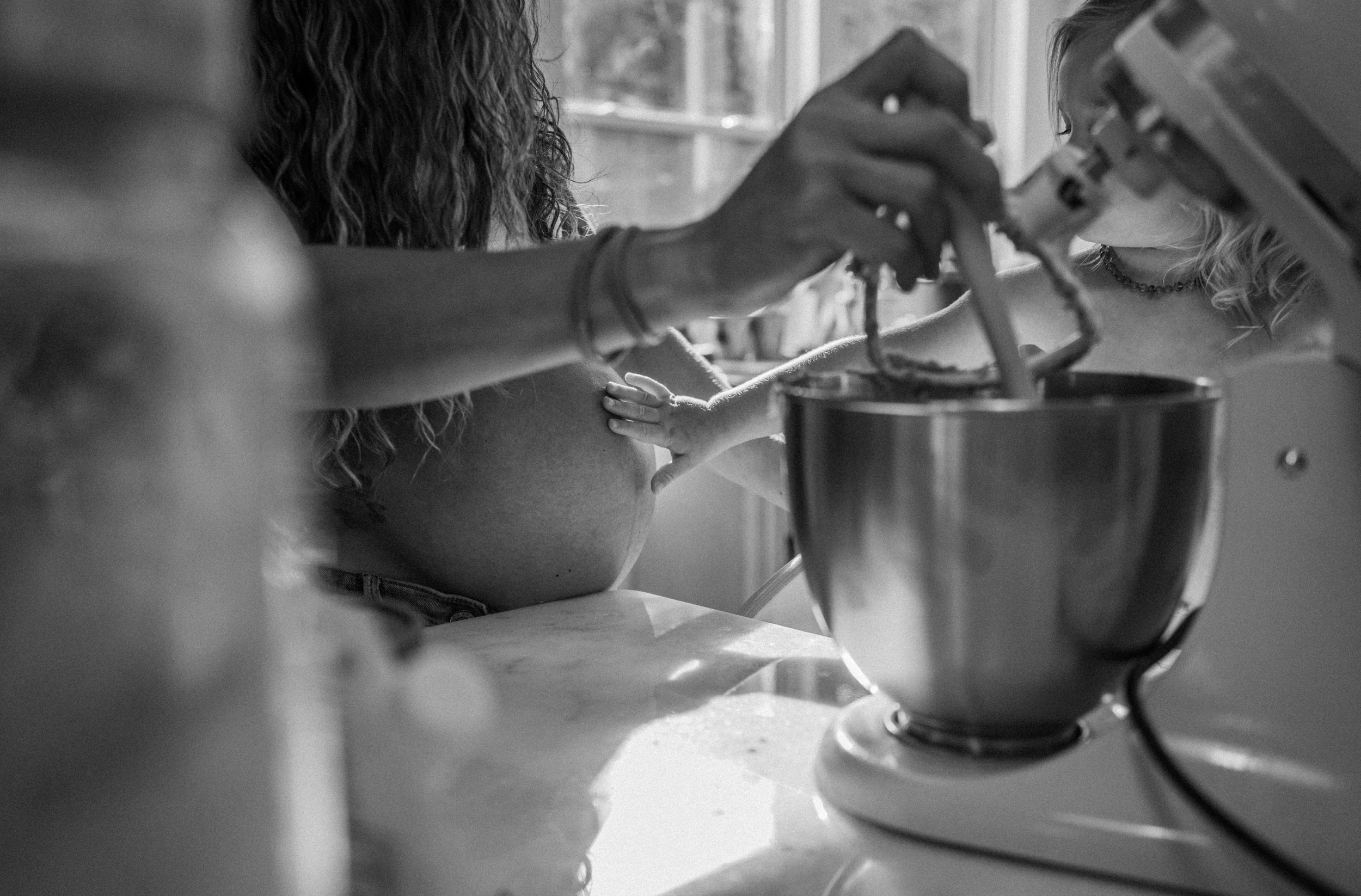 toddler touching mom's belly in maternity session baking cookies