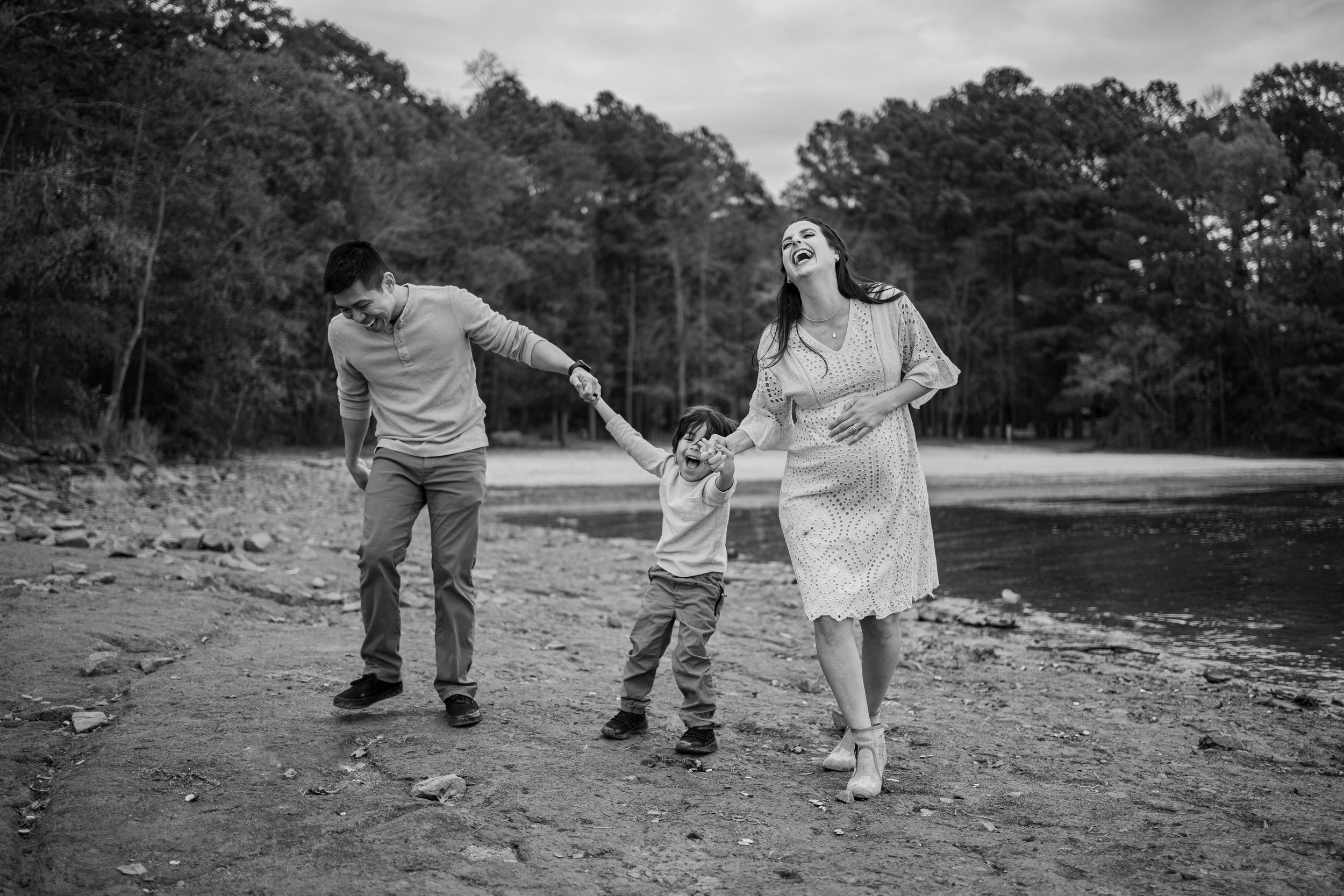family laugh together at lake maternity session