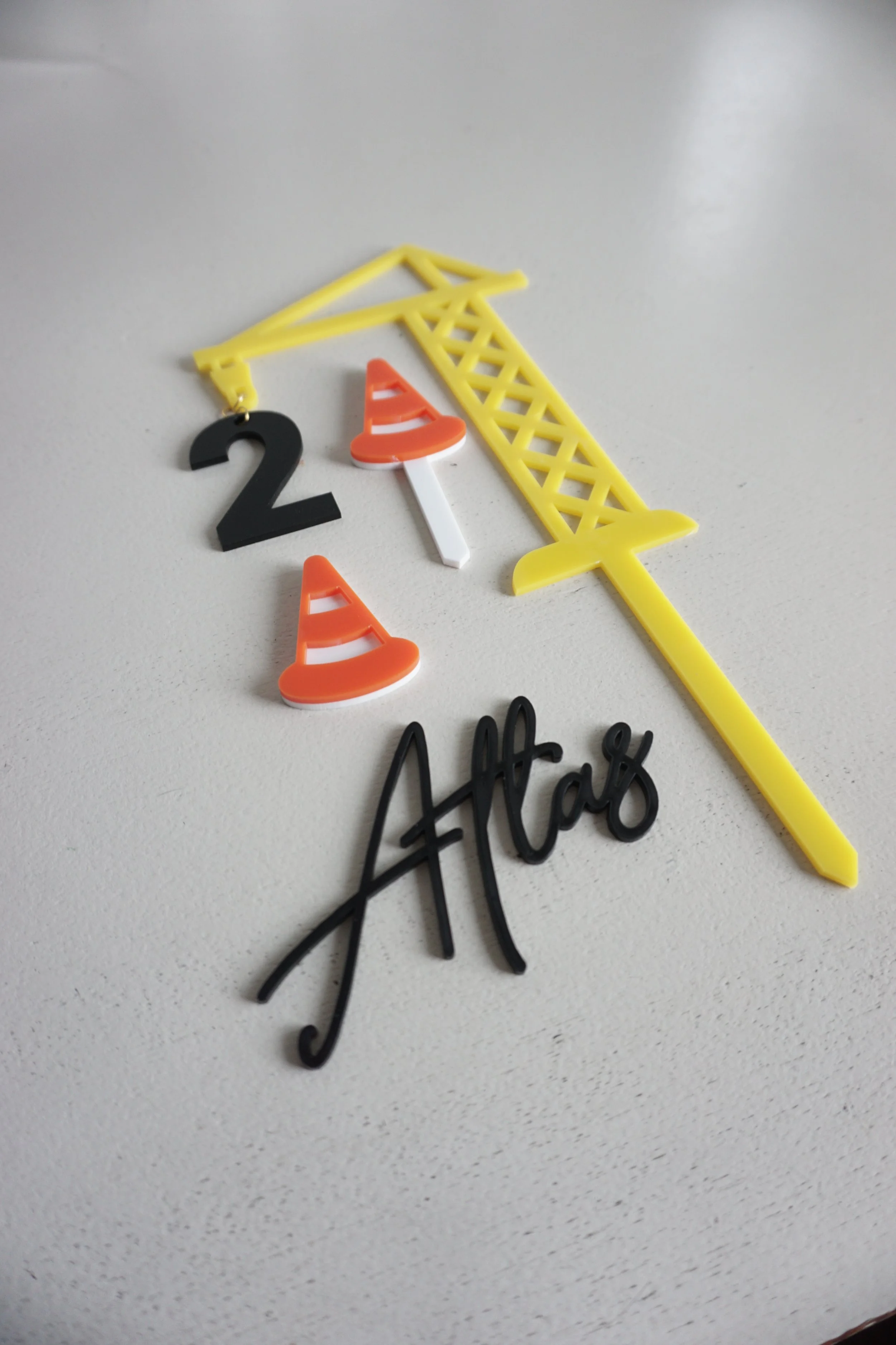 All the pieces customers can buy in the construction cake topper, including a name, safety cone, and crane.