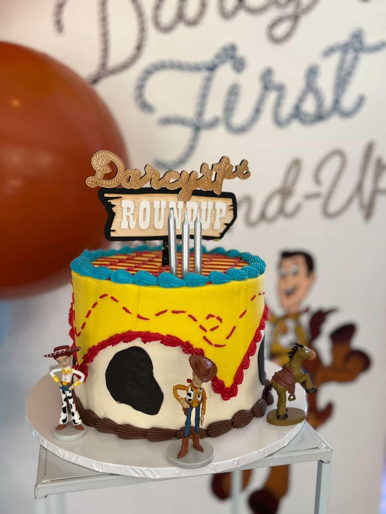 A custom cake topper made for a toy story, cowboy themed party. It features a lasso and signage that looks like it's from the old west or western american movies