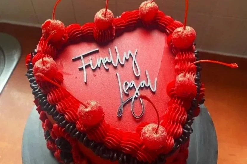 A black fropper saying finally legal on a marie-antoinette style cake that's red and black for an 18th birthday