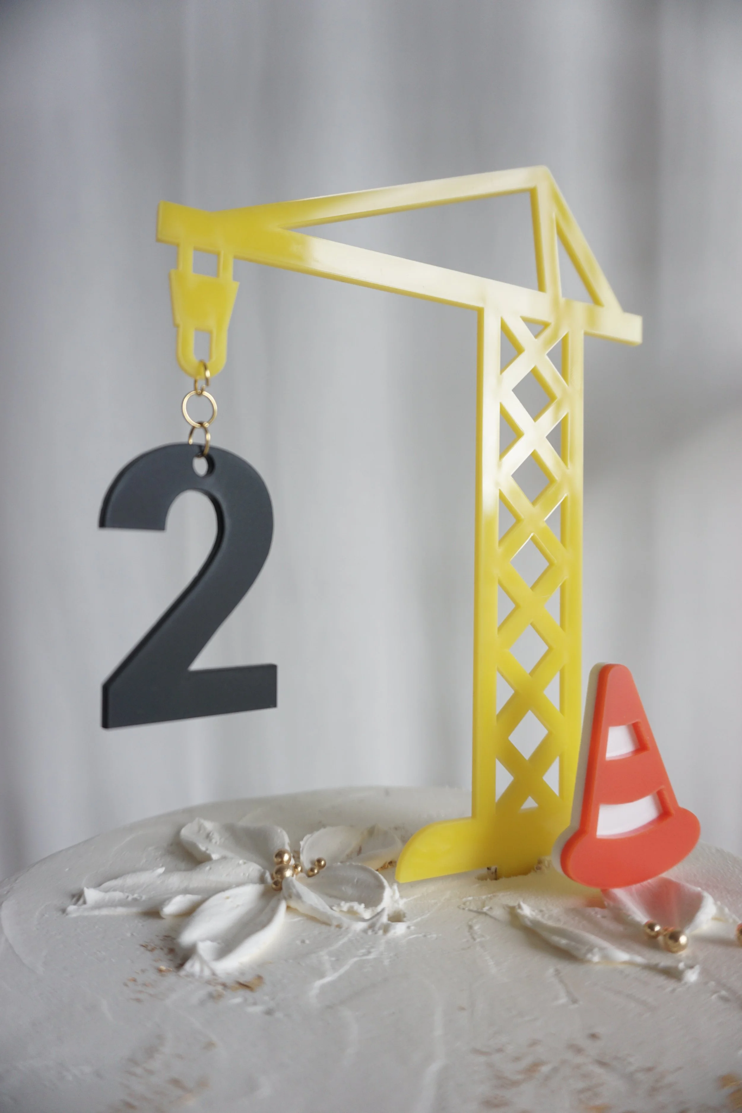 Close up of the crane cake topper, safety cone, and age.