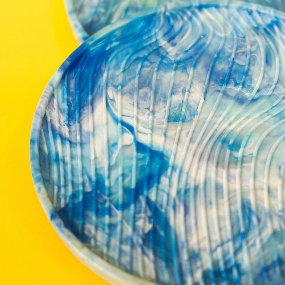 Close-up of a marbled blue and white plastic cup on a yellow surface.