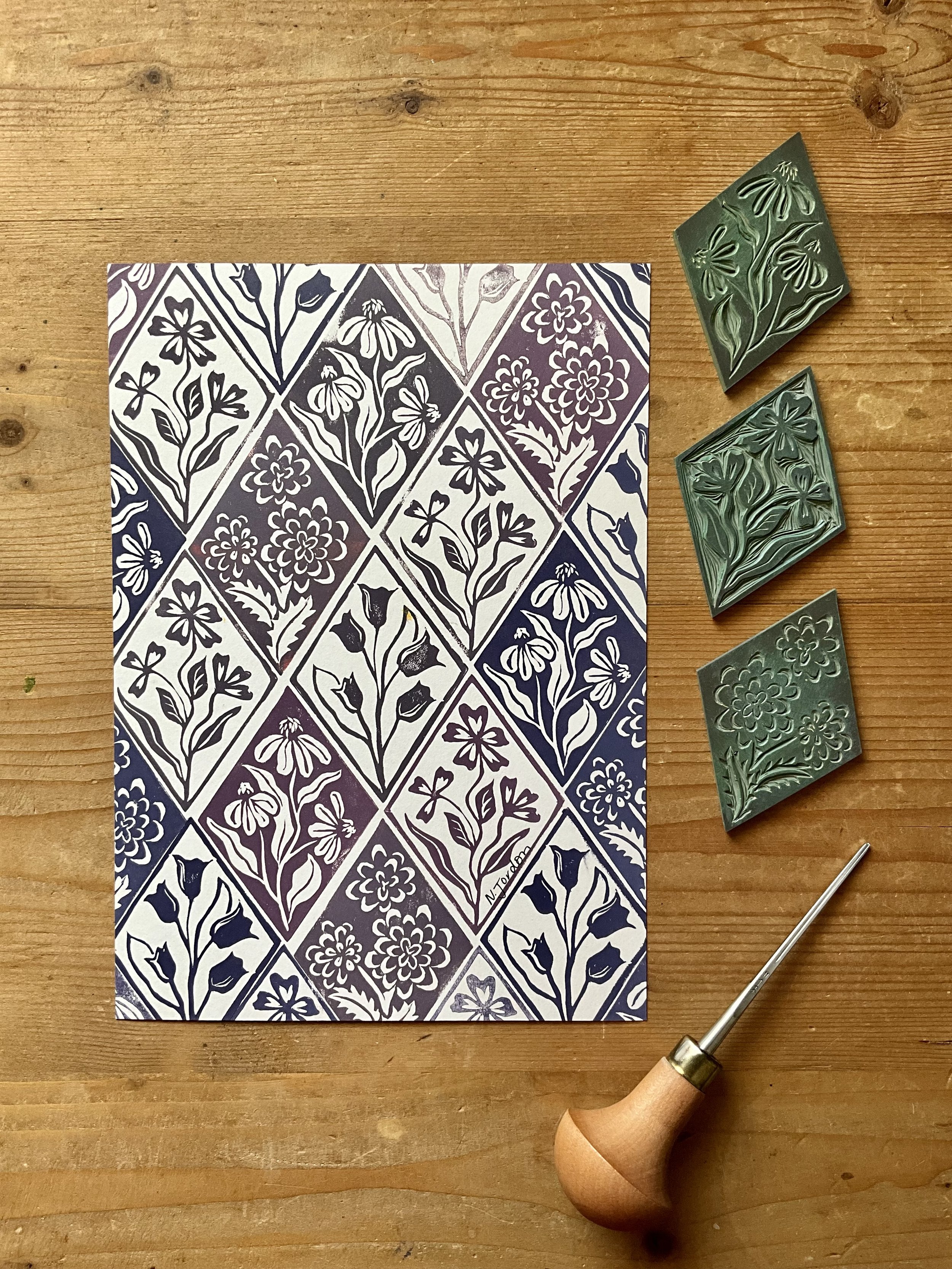 Floral diamonds original lino cut print, in A5. Hand printed in shades of purple. Photo shows lino carving tool and the diamond blocks used to print this piece.