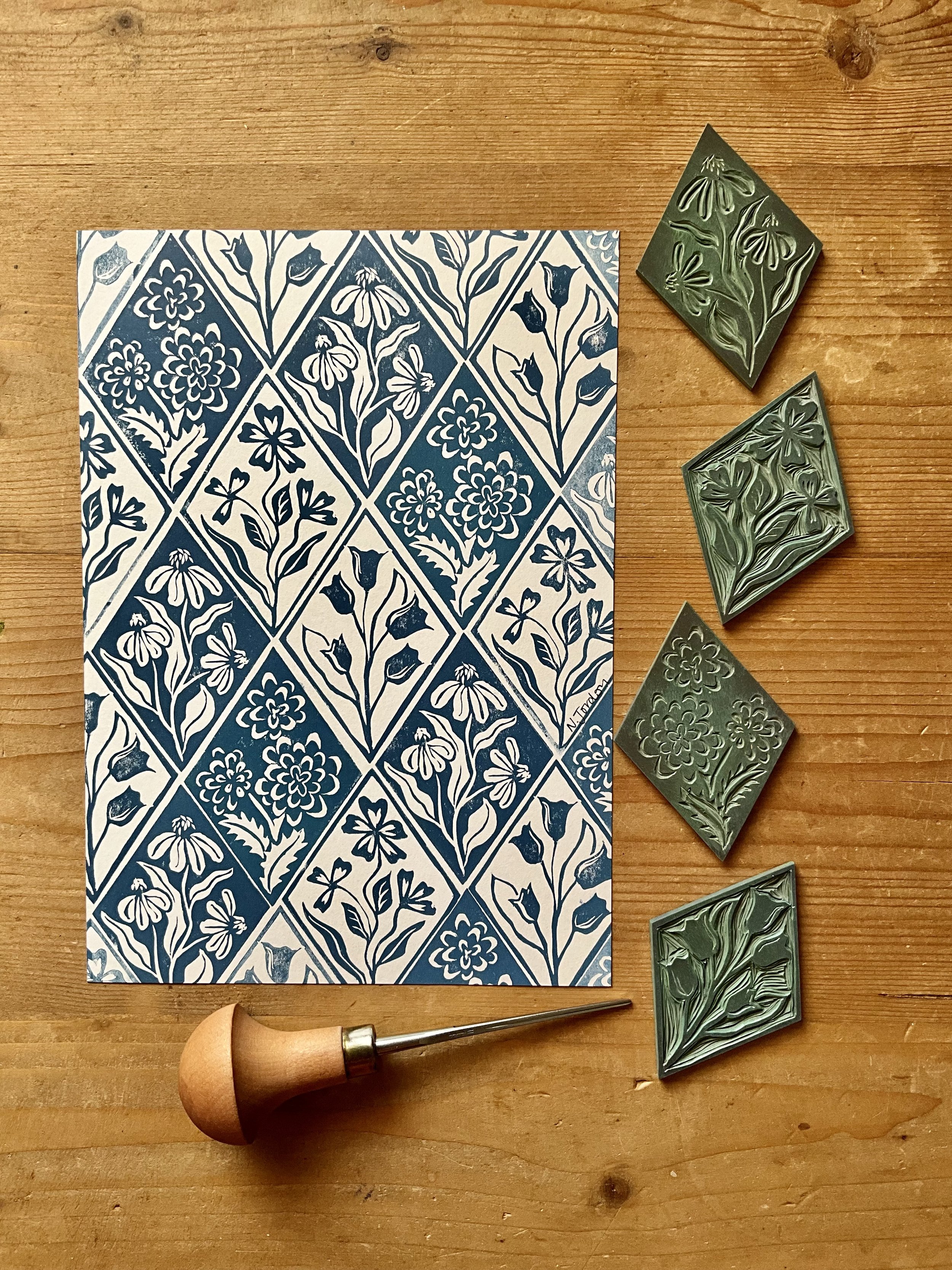 Floral diamonds original lino cut print, in A5. Hand printed in shades of blue. Photo shows lino carving tool and the diamond blocks used to print this piece.