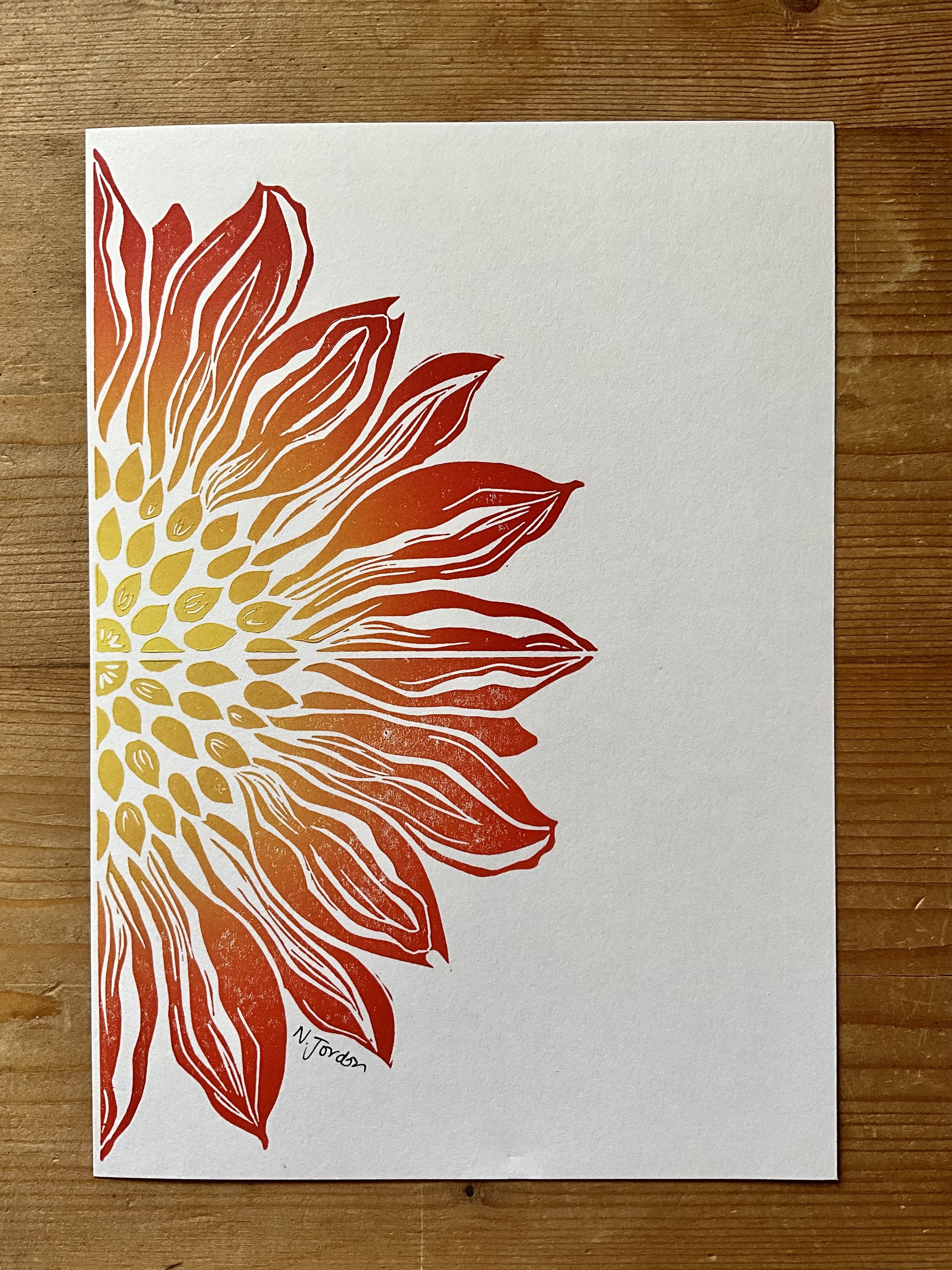 Close up of sunflower original lino cut print, in A5. Hand printed in red-yellow ombré.