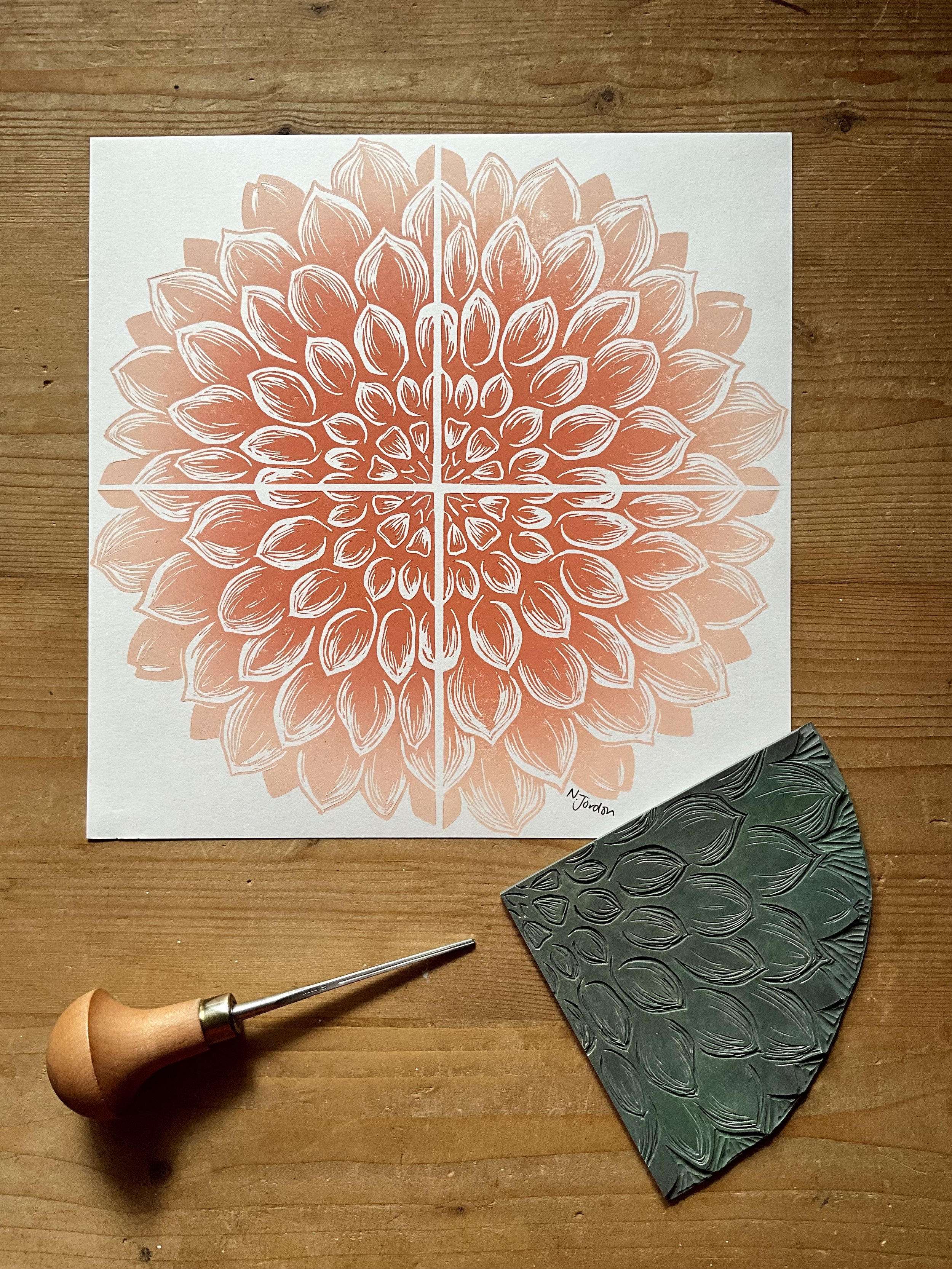 Full dahlia original lino cut print, in 21x21cm square. Hand printed in pink/peach ombré. Photo also shows lino carving tool and the dahlia block used to print this piece.