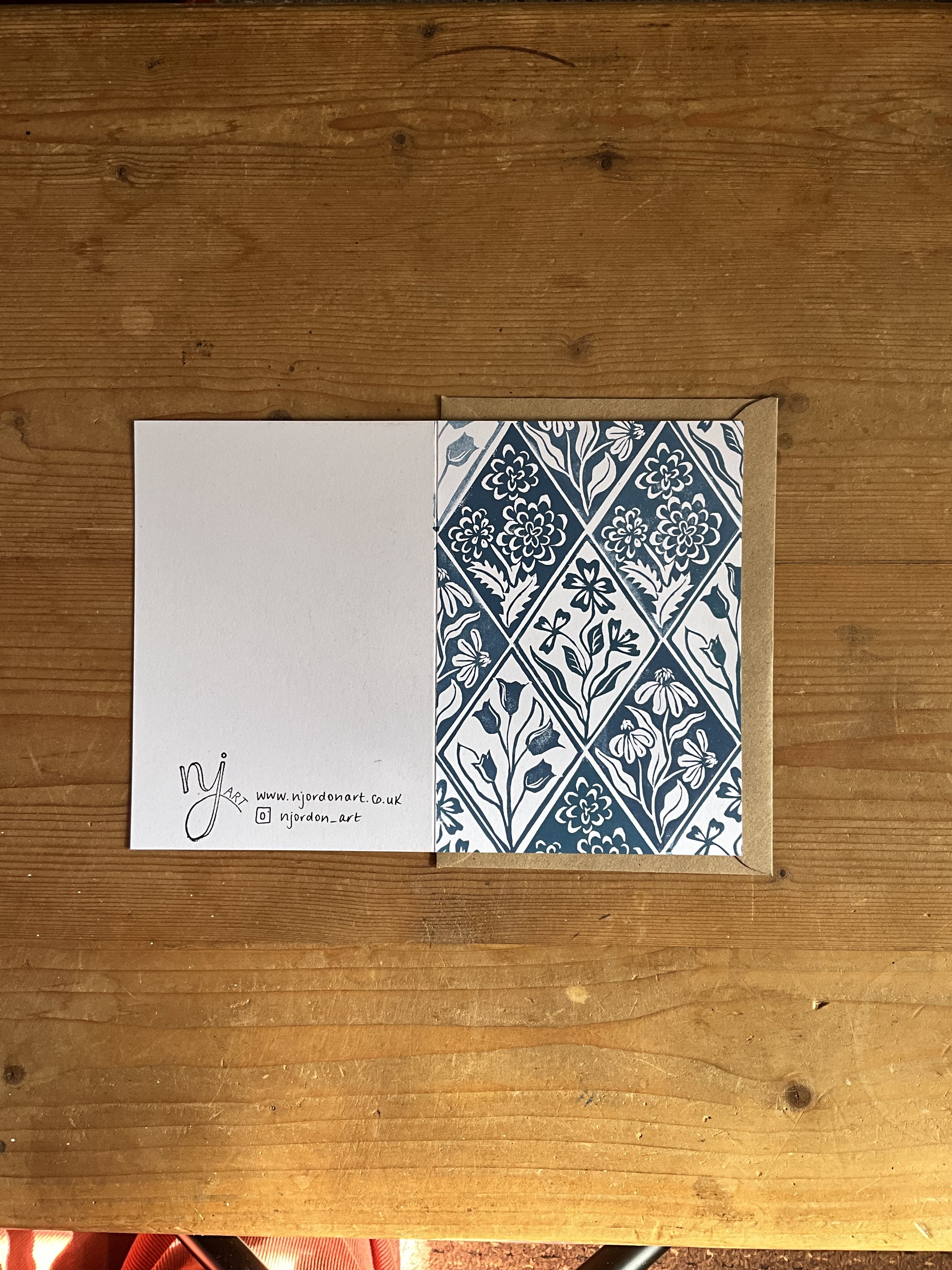 Single floral diamond greeting card in A6. Laid flat to show front and back of card, with brown kraft envelope behind the card