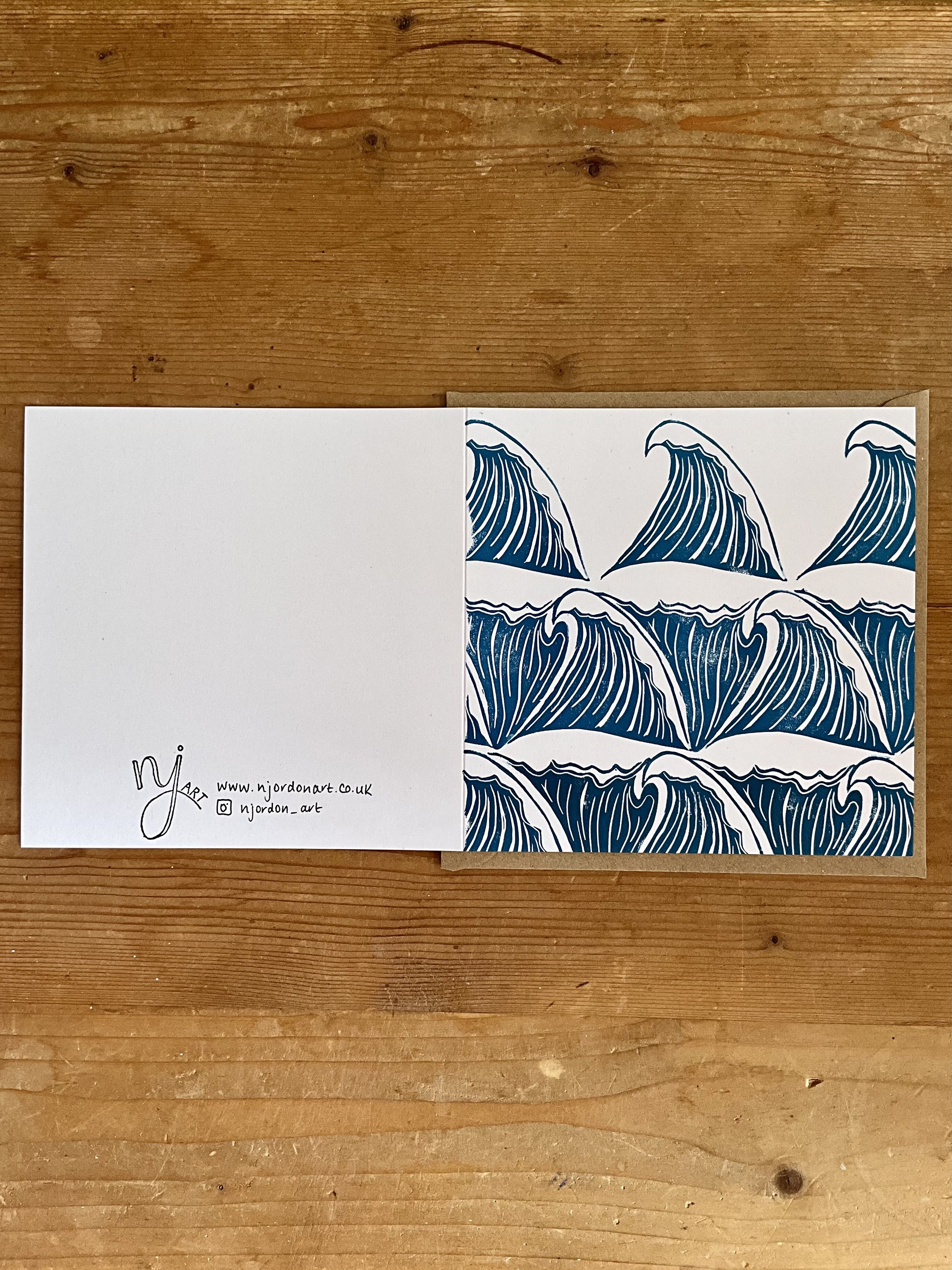 Photo of square waves linocut card, laid flat to show front and back of design. Laid on top of a kraft brown envelope