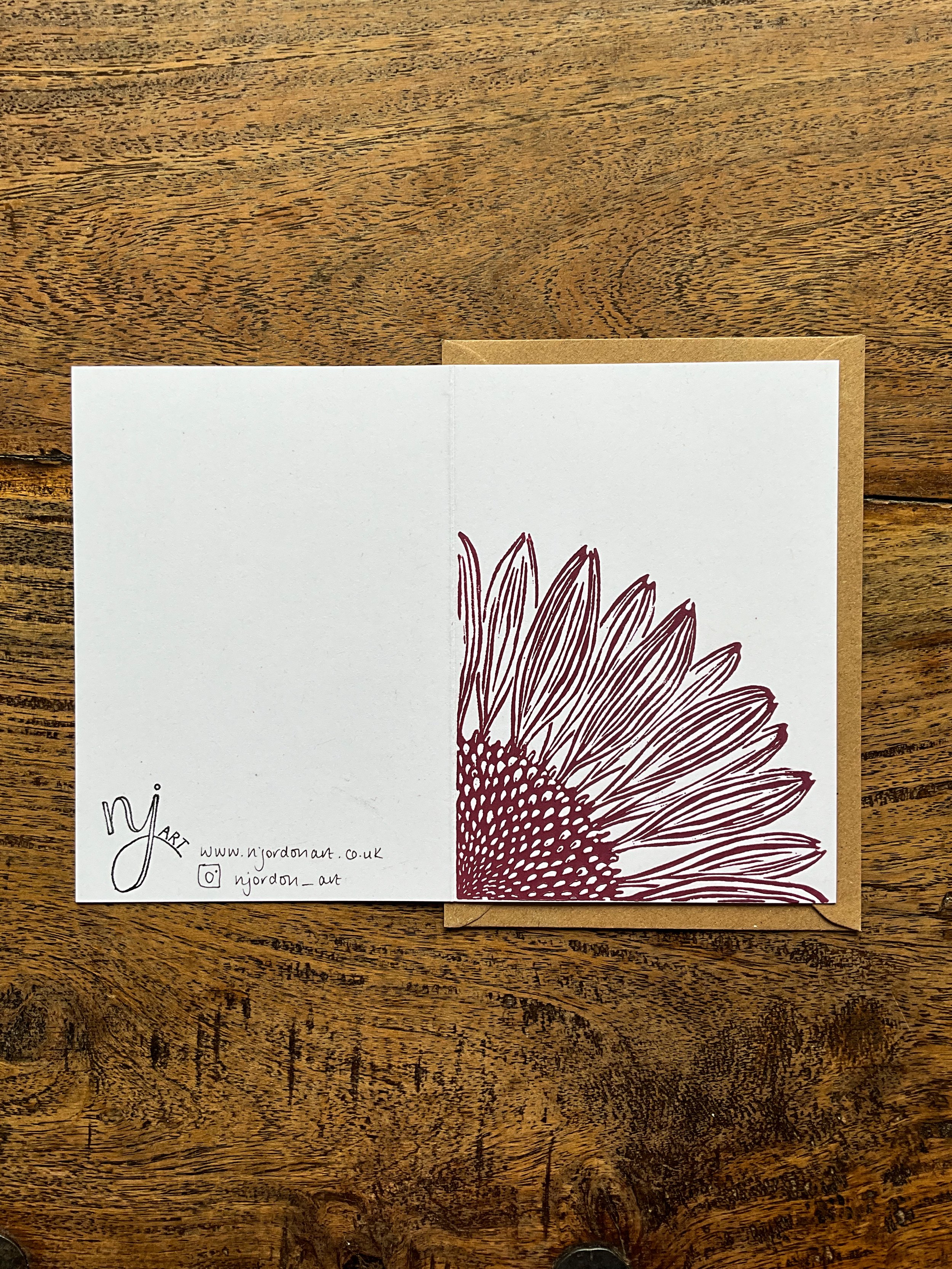 Single coneflower linocut greeting card, laid flat to show front and back of the design. With kraft brown envelope behind the card
