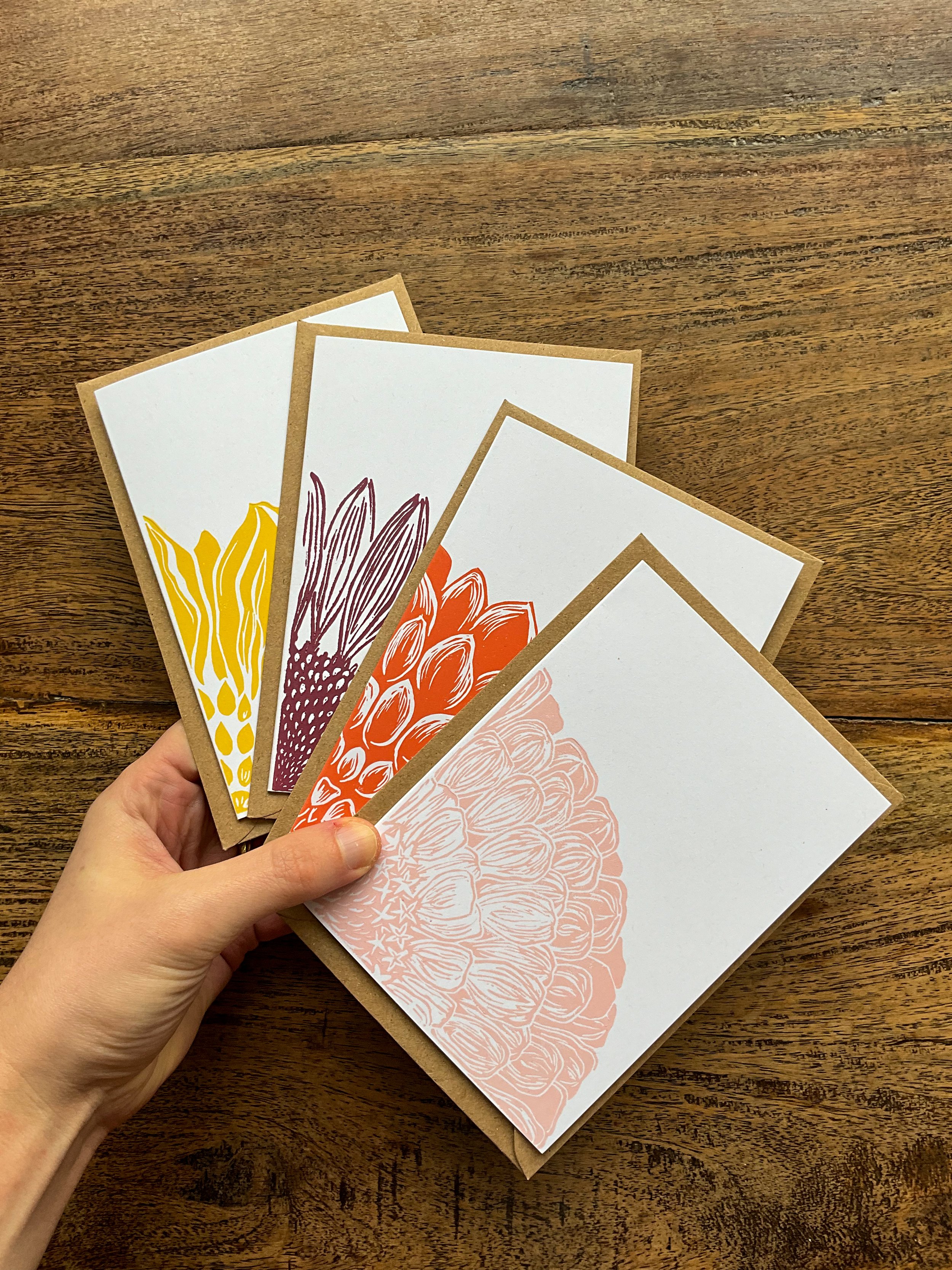 Four A6 linocut cards held in my hand, making up a bouquet bundle of cards