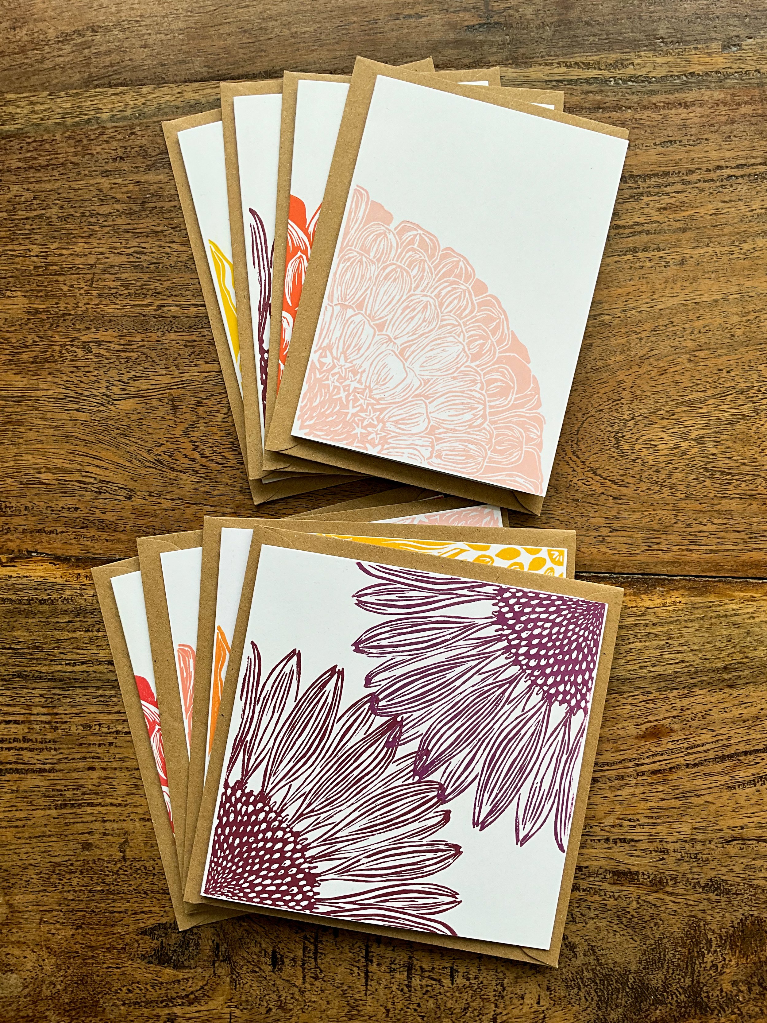 Photo of two example ‘bouquet bundles’ of linocut greeting cards. One bundle is A6 in size, the other is square. Each contains four different floral linocut designs