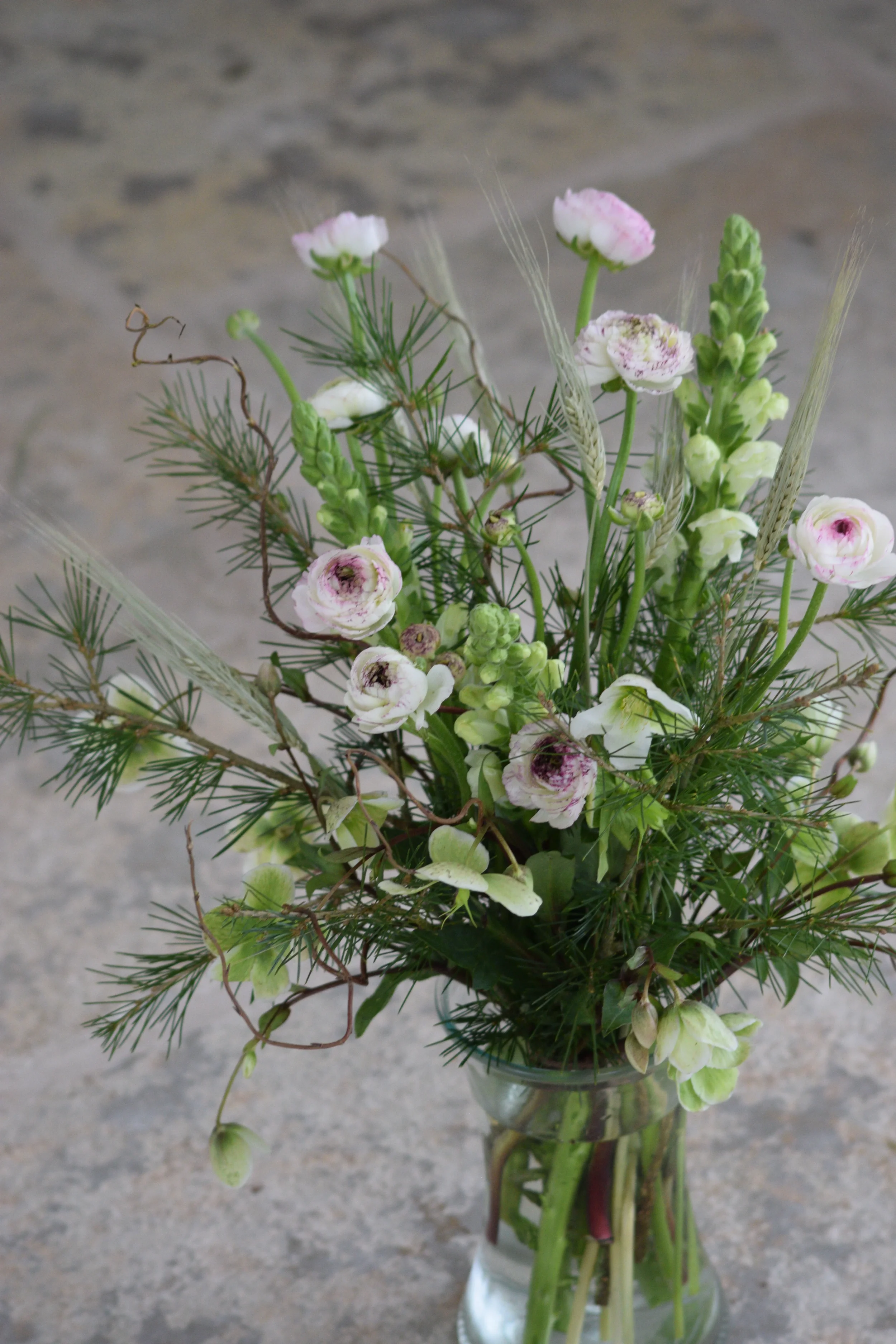 A bouquet of pink and white flowers in a glass vase on a gray surface.