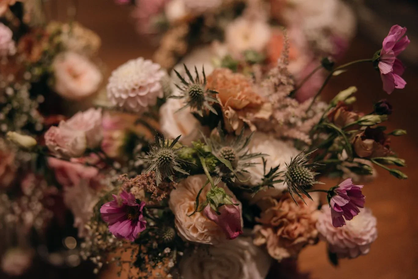 A close-up of a bouquet of pink, white, and purple flowers with some thistle-like greenery.