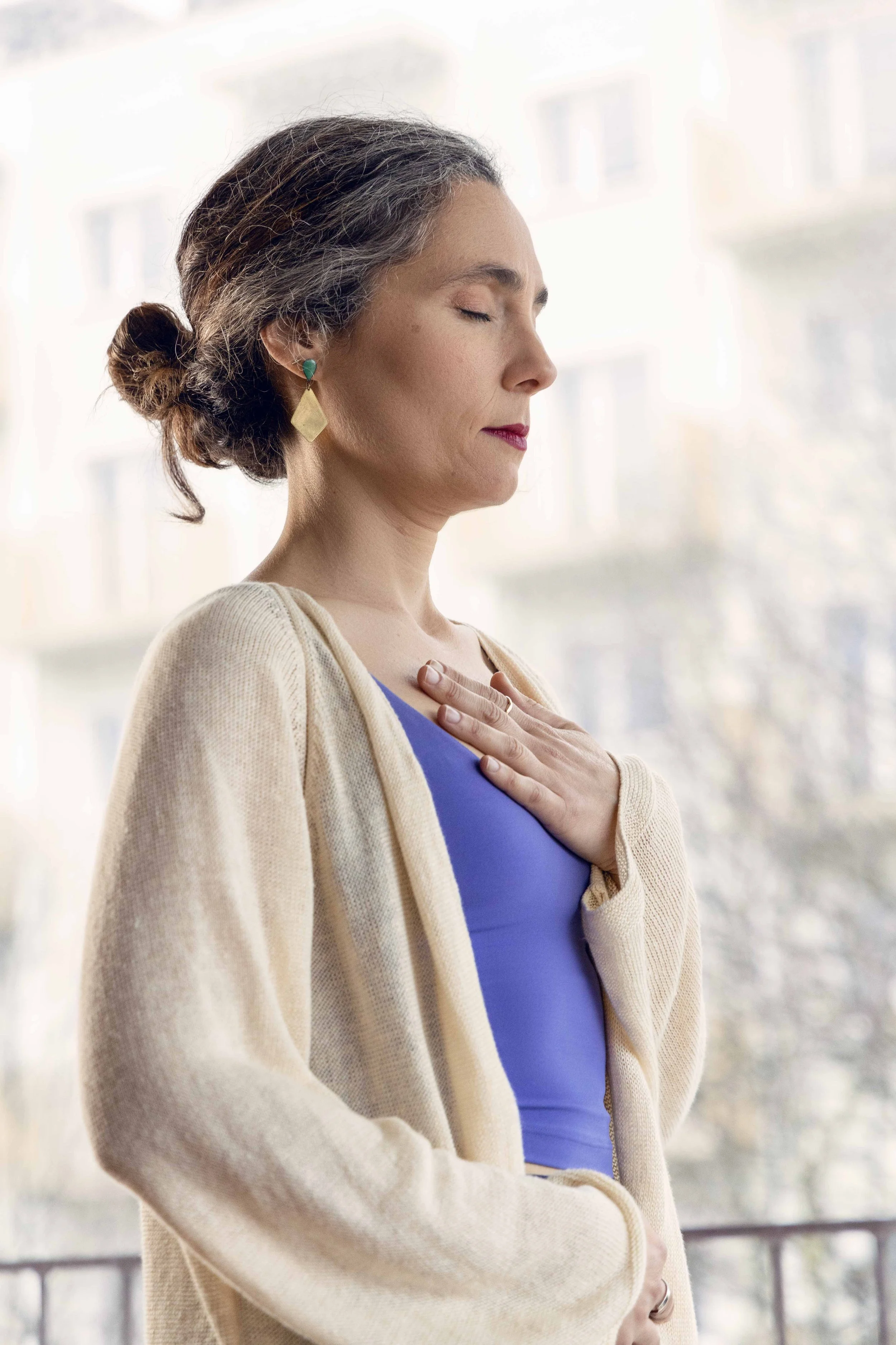 Ana Maia Marques standing pose, resting hands in chest and belly with eyes closed