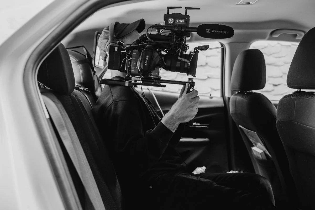 Ben Harrison filming with a camera rig from inside a car on location