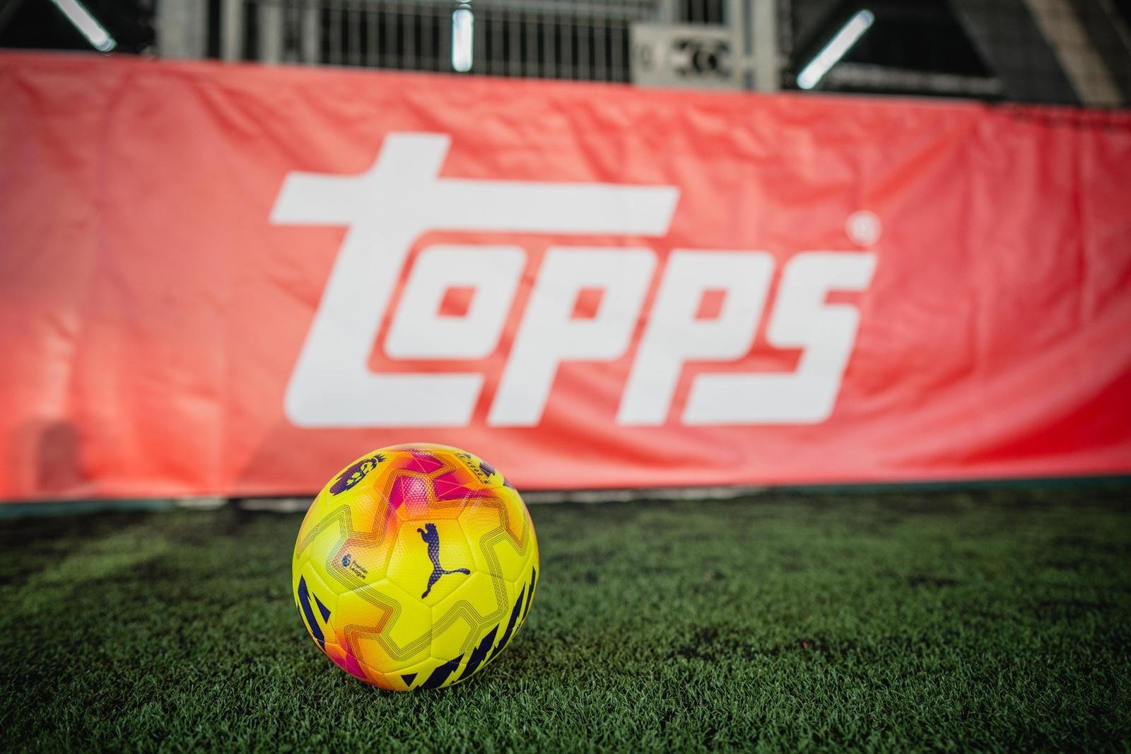 Football positioned on artificial turf in front of Topps branding at a live brand activation event.