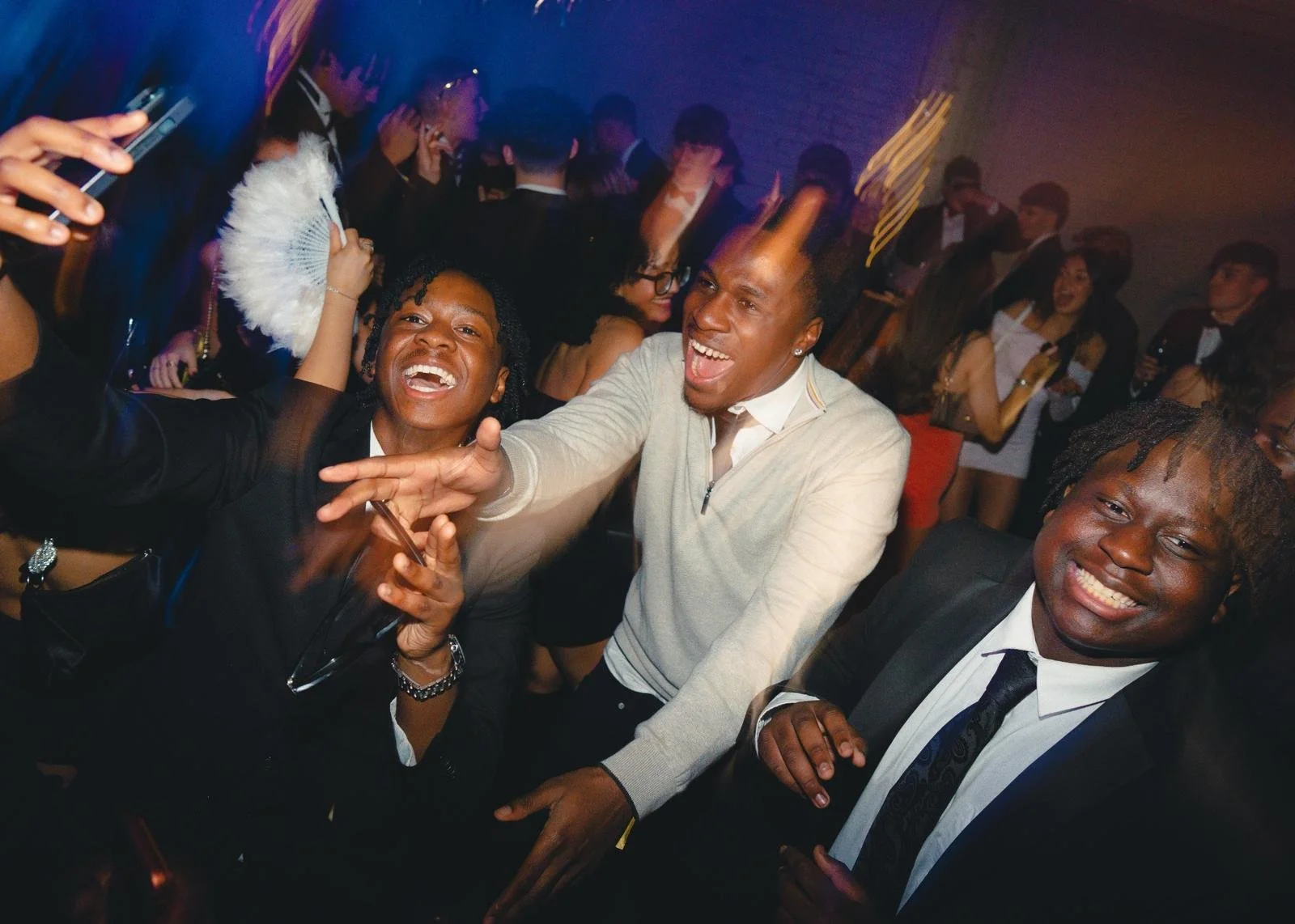 Group of people smiling and enjoying themselves at a lively party or celebration in a dimly lit venue.