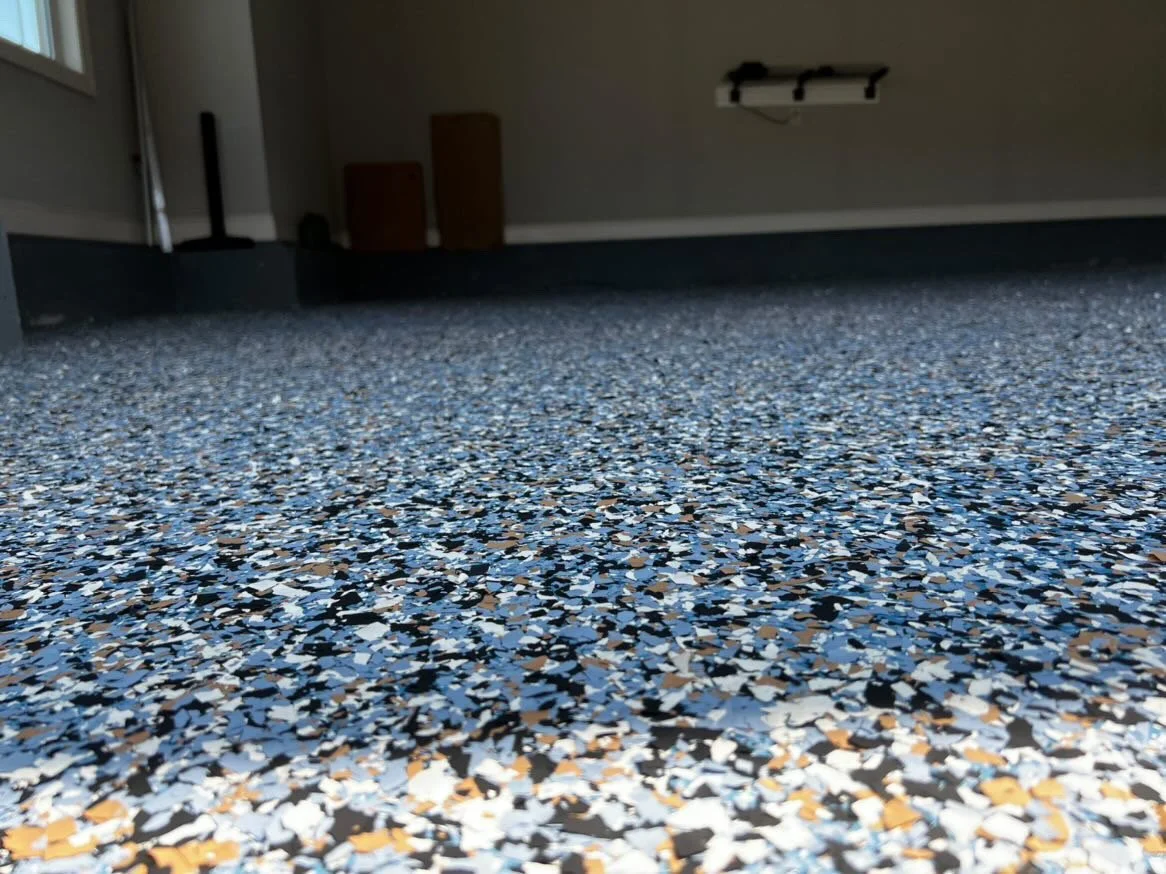 Speckled epoxy garage floor with blue, gray, and tan flakes.