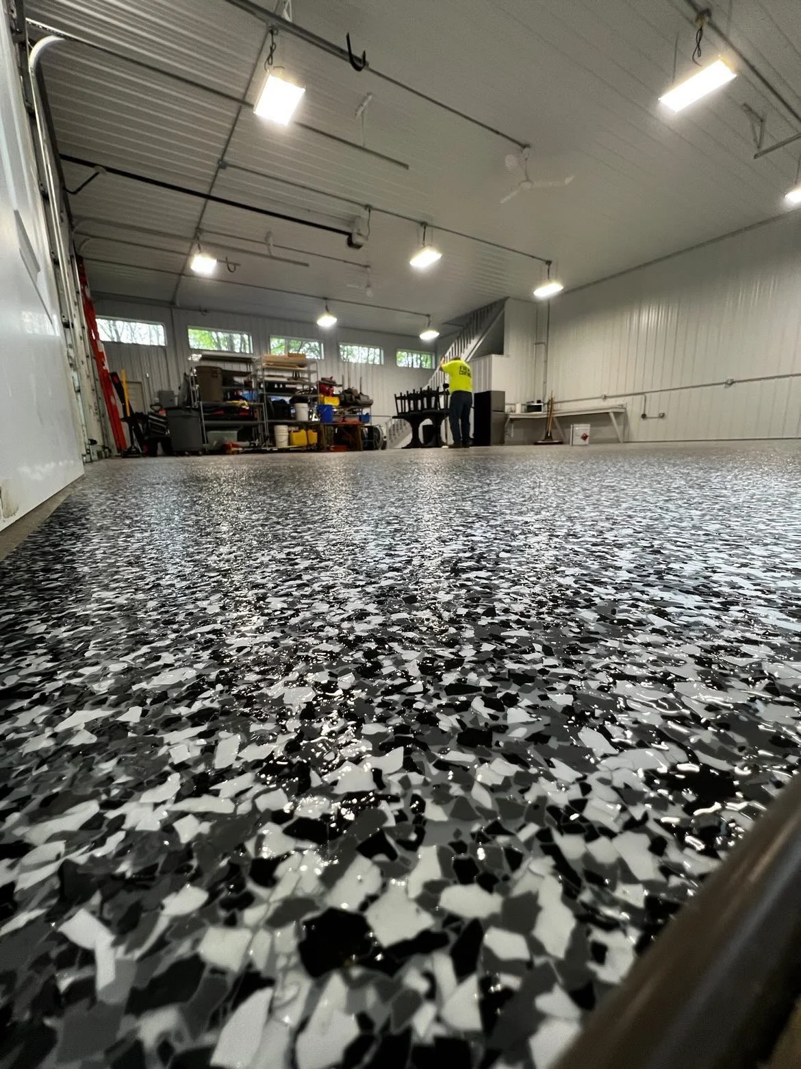 Epoxy-coated floor in a large garage space with industrial lighting and shelving.