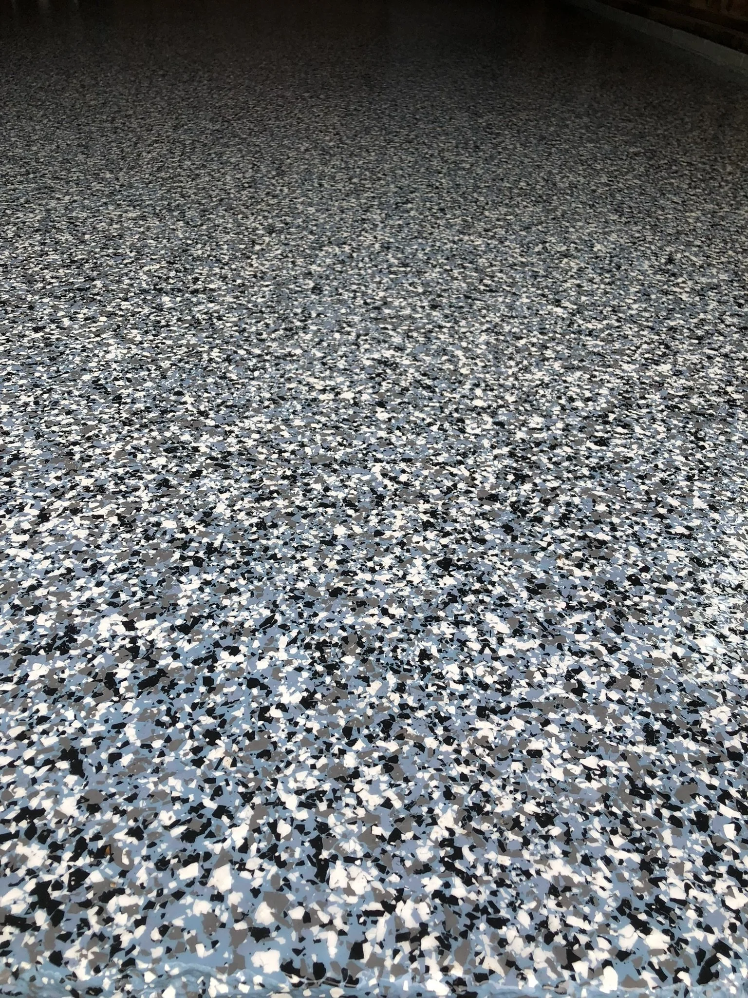 Speckled epoxy garage floor with black, gray, and white flakes.