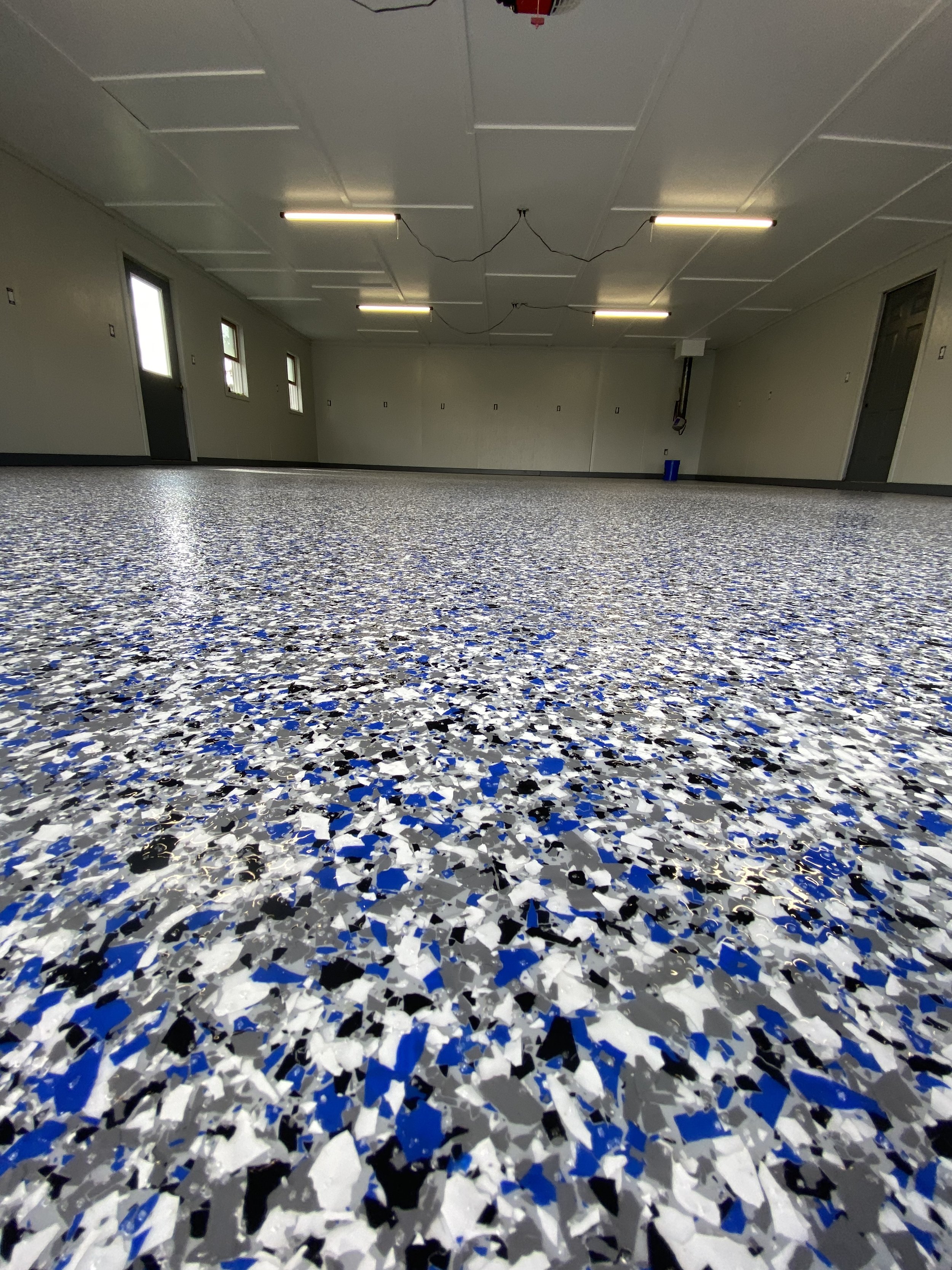 Room with speckled epoxy floor, gray walls, and fluorescent ceiling lights.