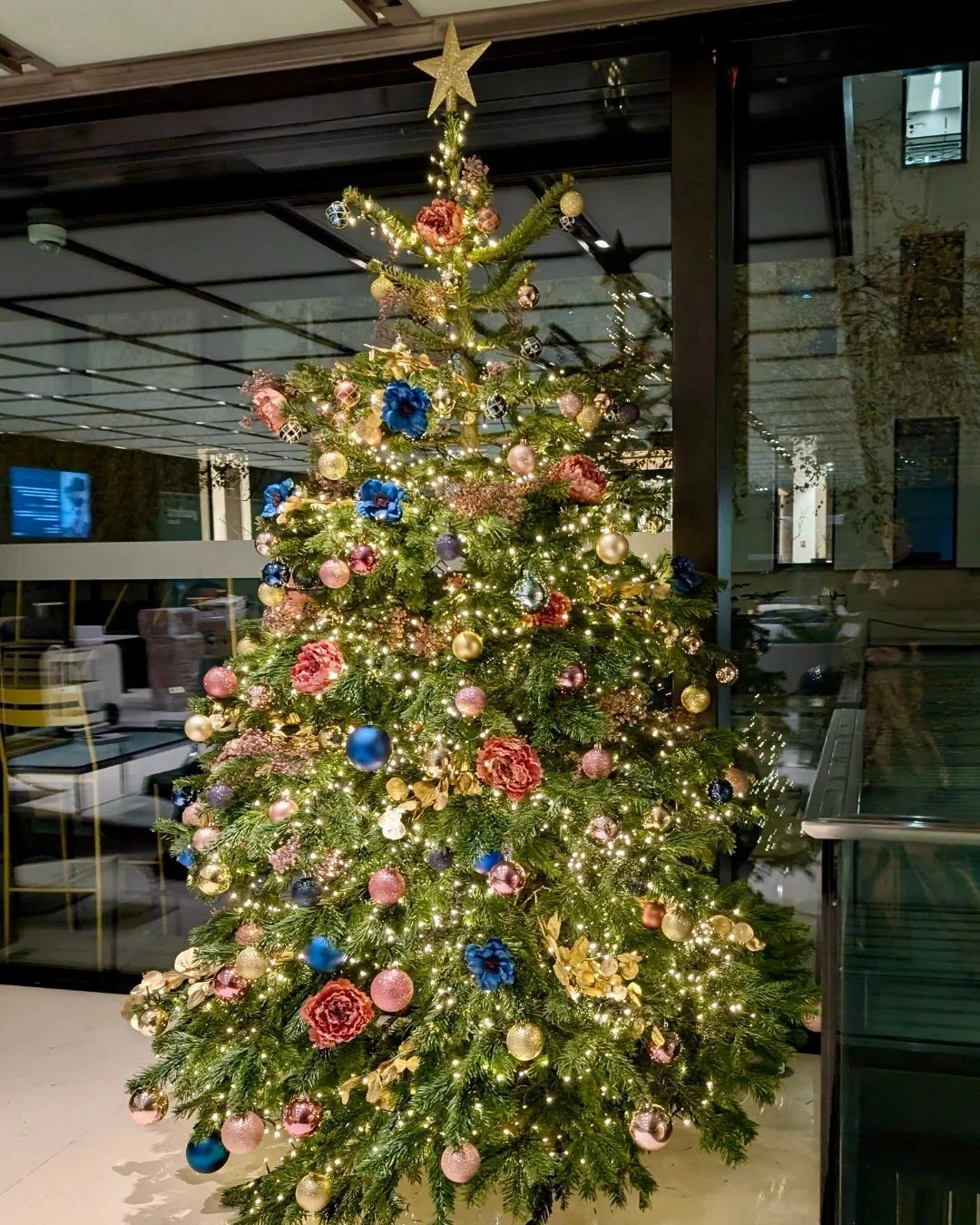 Sapin de Noël décoré sur mesure aux tons pastel dans le hall d'une entreprise