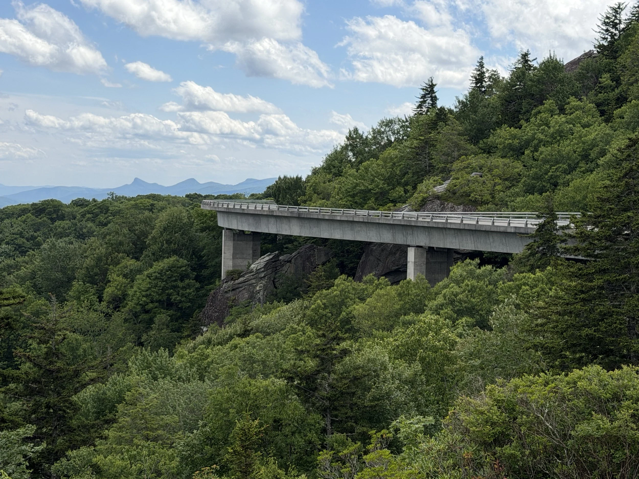 The Linn Cove viaduct along the Blue Ridge Parkway with a view of Table Rock and Hawksbill Mountain in the back ground.