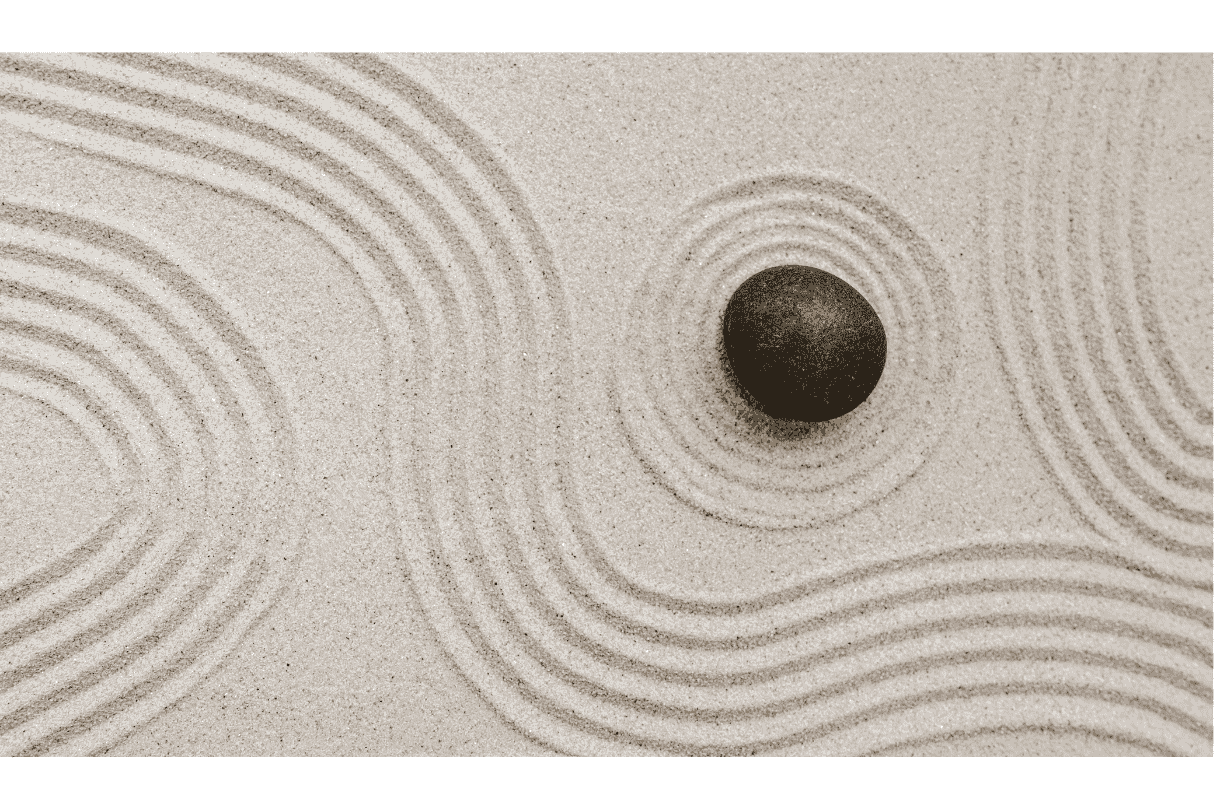 Sand with concentric circle patterns and a single black rock in the center.