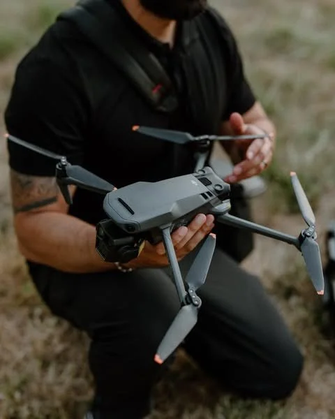 A professional videographer preparing a high-end drone for flight, representing FAA Part 107 licensed aerial services for industrial safety inspections and facility overviews