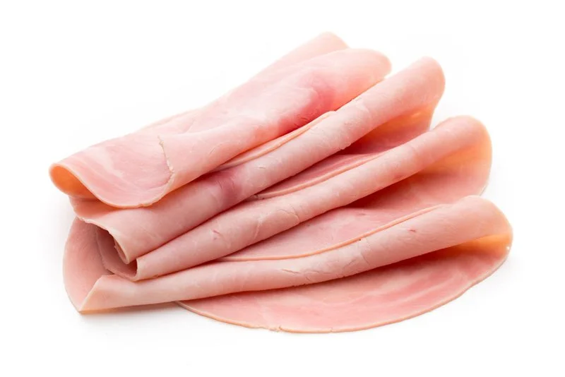 Several slices of cooked ham stacked on a white background.