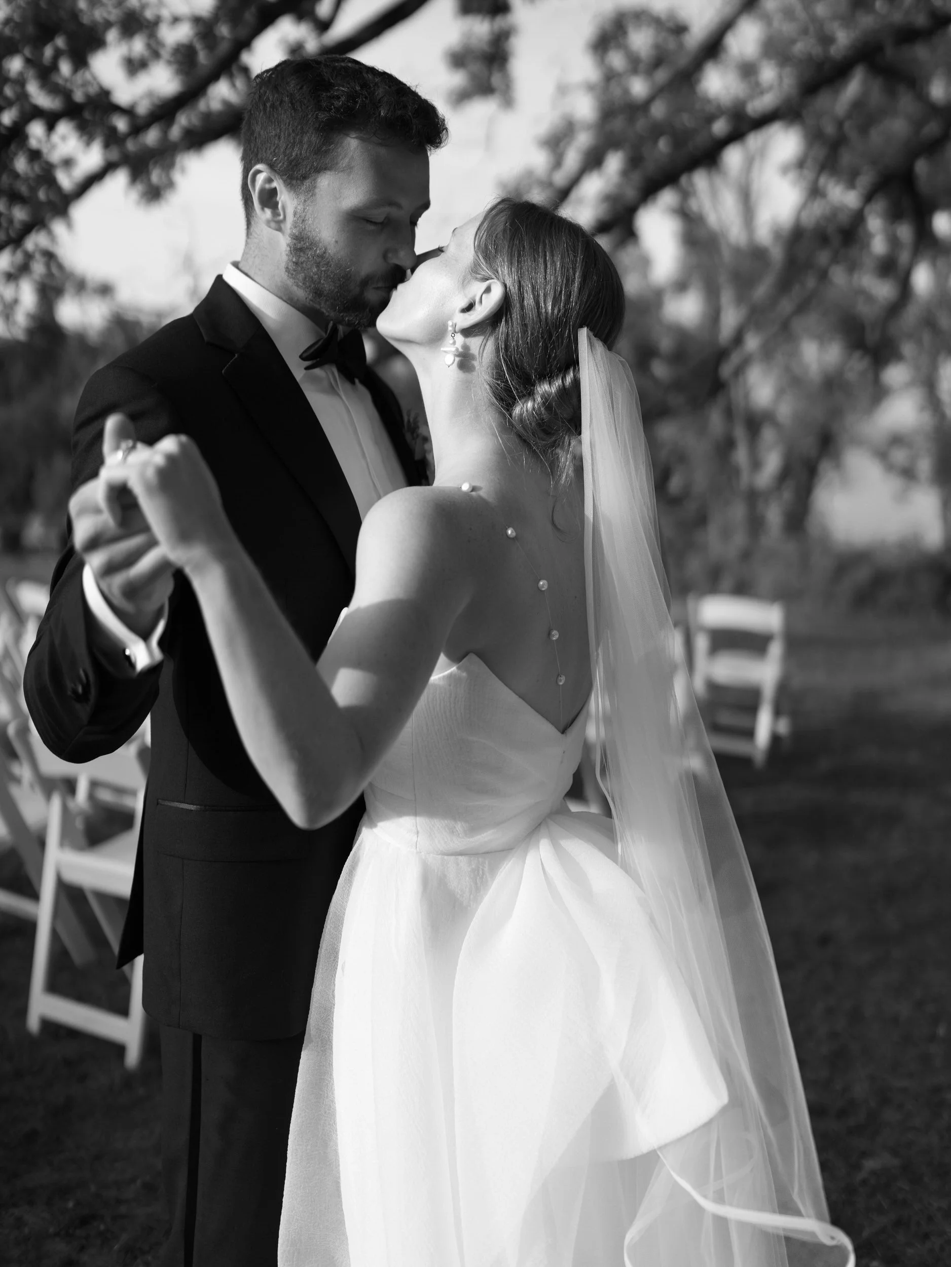 A newlywed couple kissing as they hold hands 