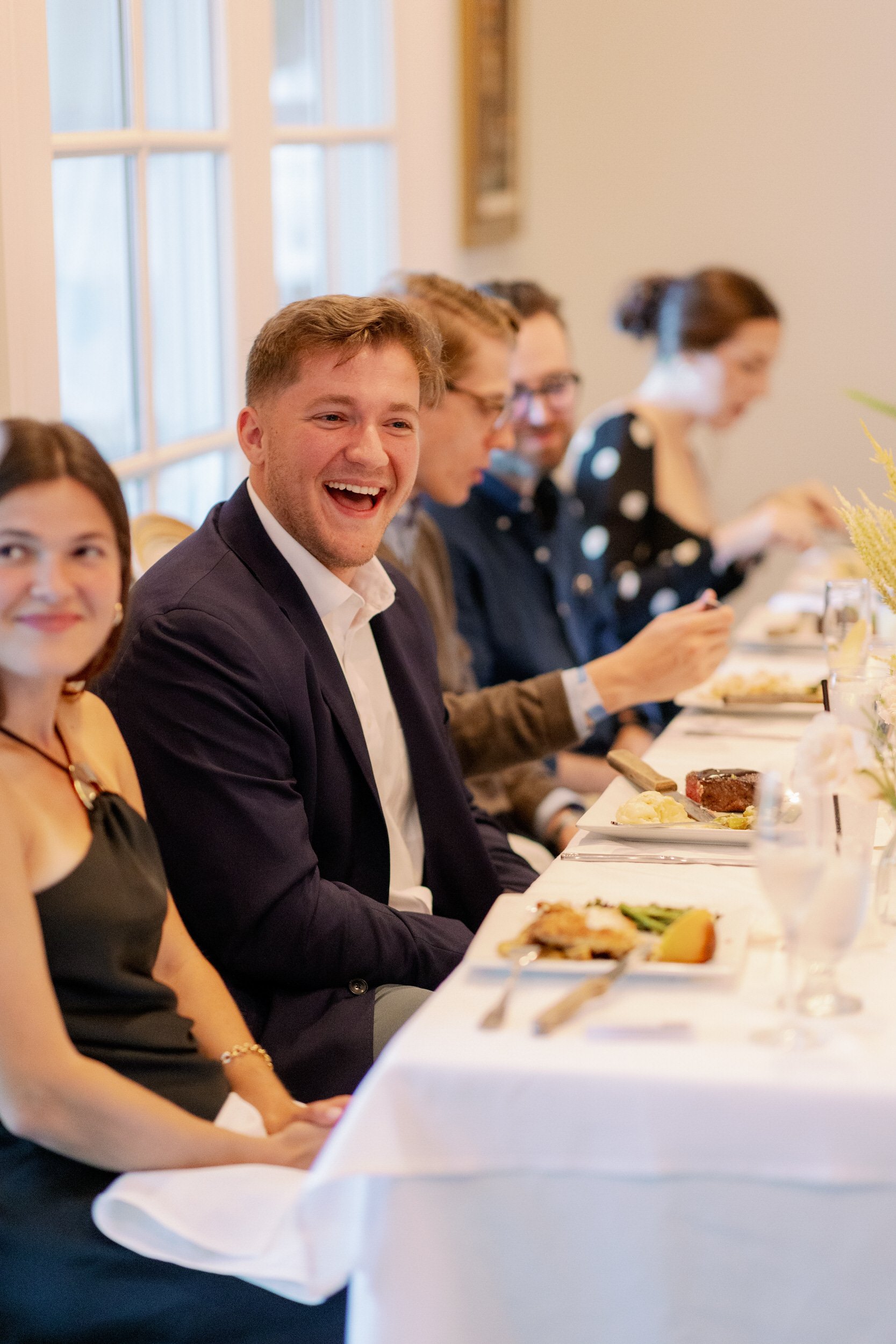 Wedding guests smiling while sitting at reception tables 