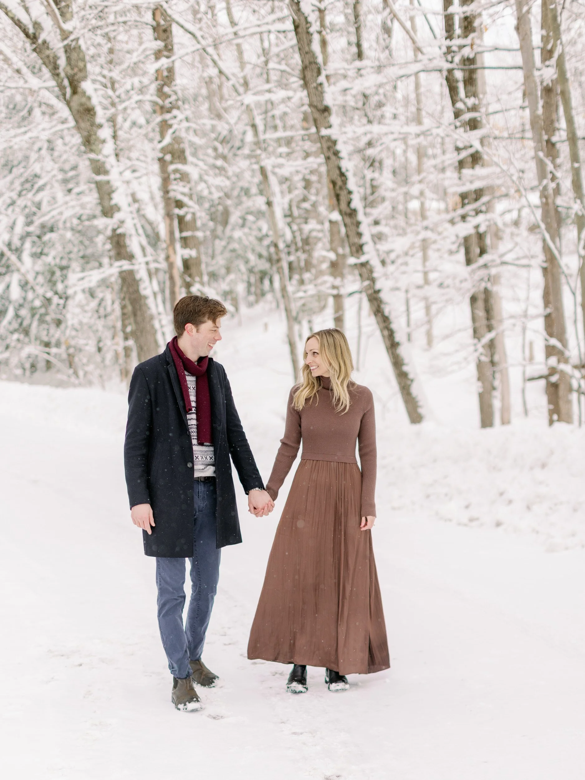 A couple holding hands and walking along a path in the snow 