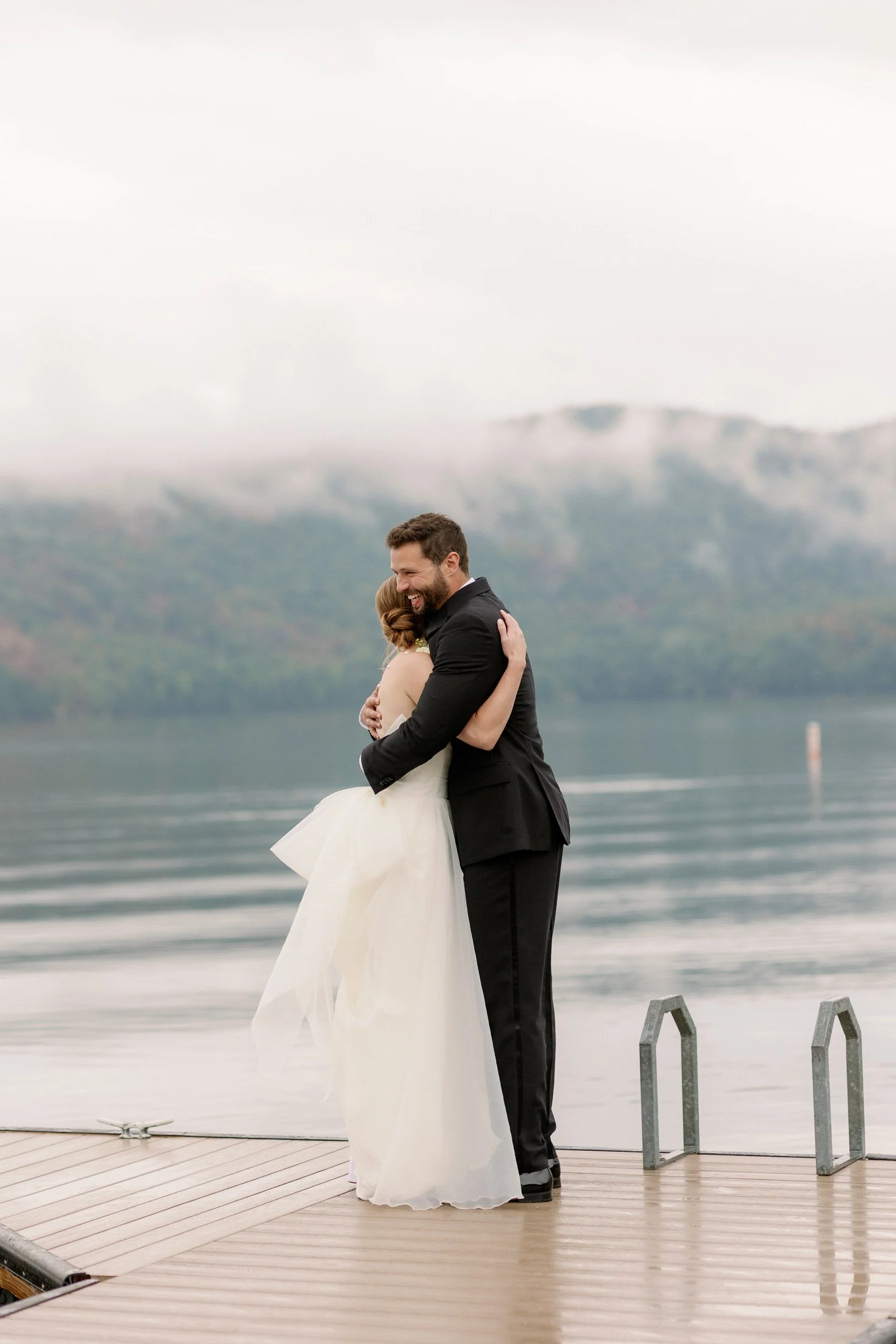 Newlyweds hugging on a dock on a lake 