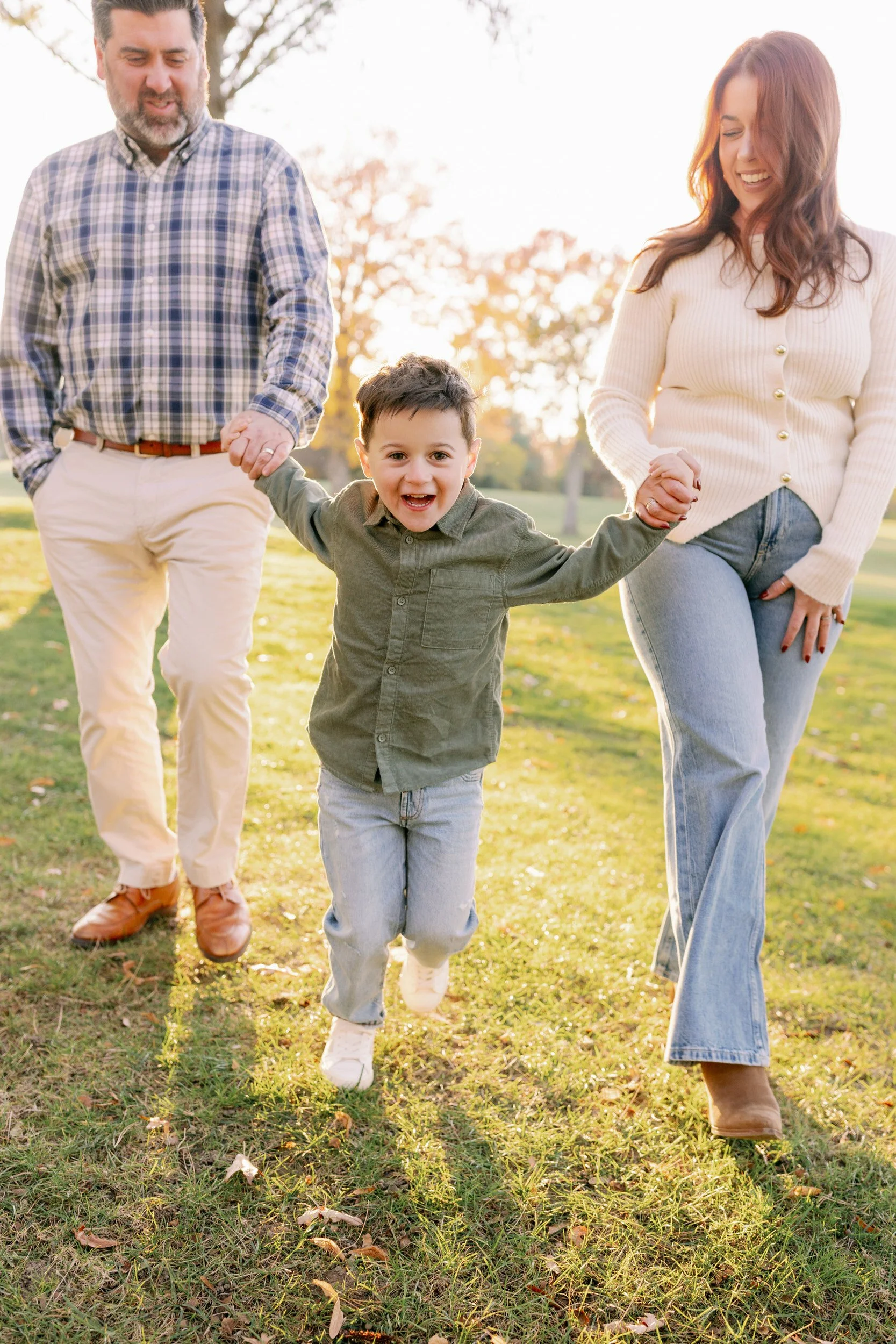 A small child holding their parent's hands and running in a field