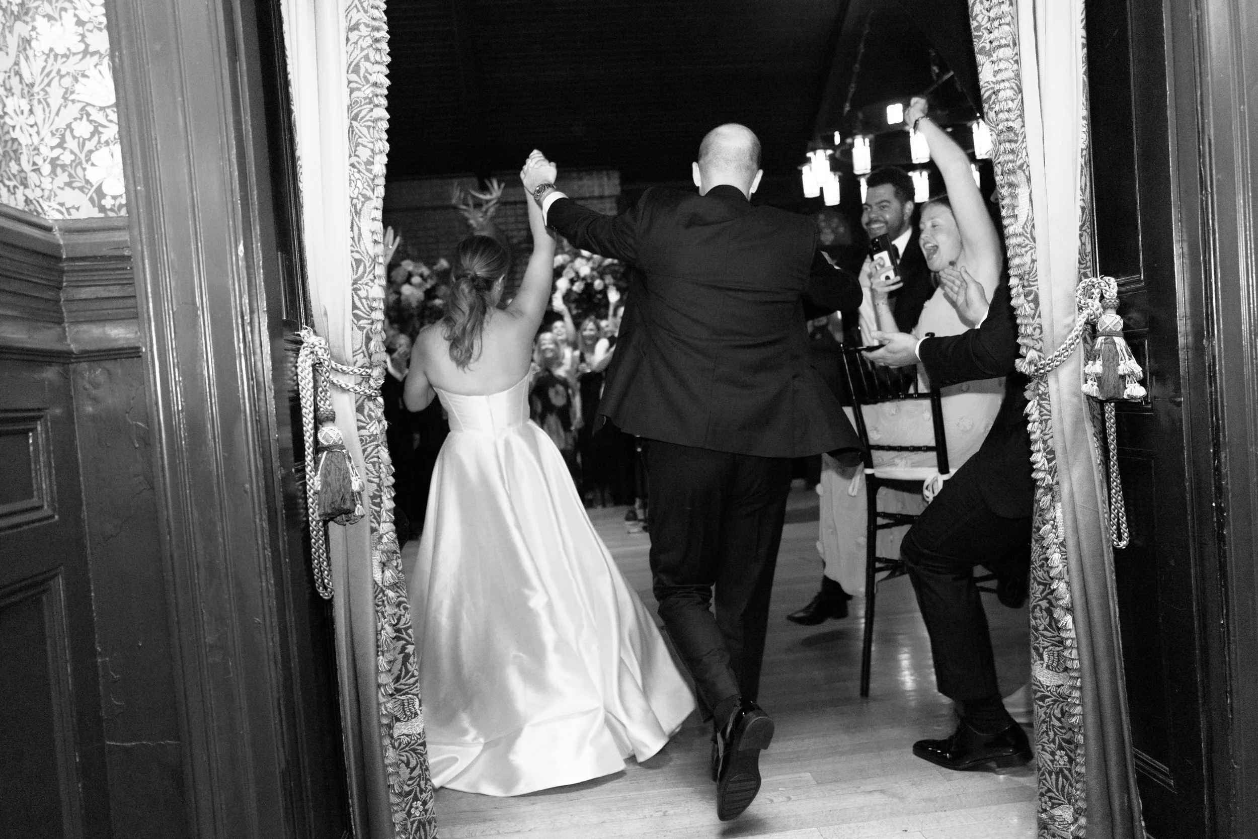 Newlyweds holding hands and walking into a wedding reception 