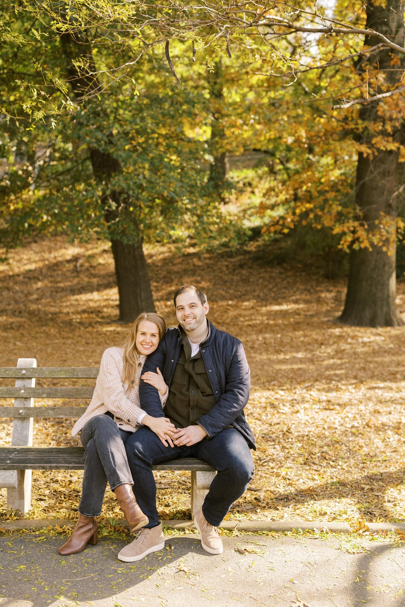A couple sitting on a park bench with their arms linked