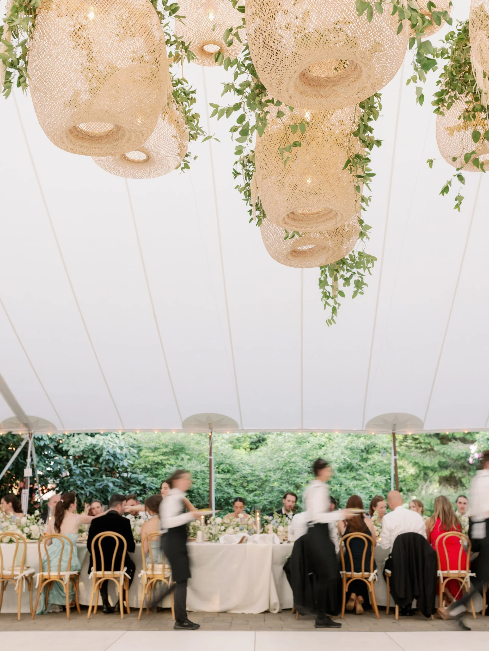  Waiters walking around a wedding reception table as they serve food 