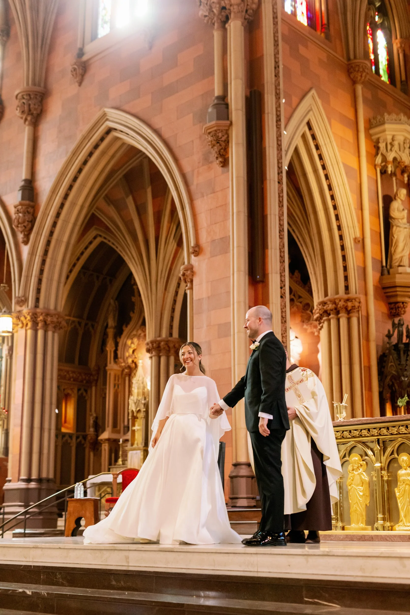 A newlywed couple holding hands on an altar during their wedding 