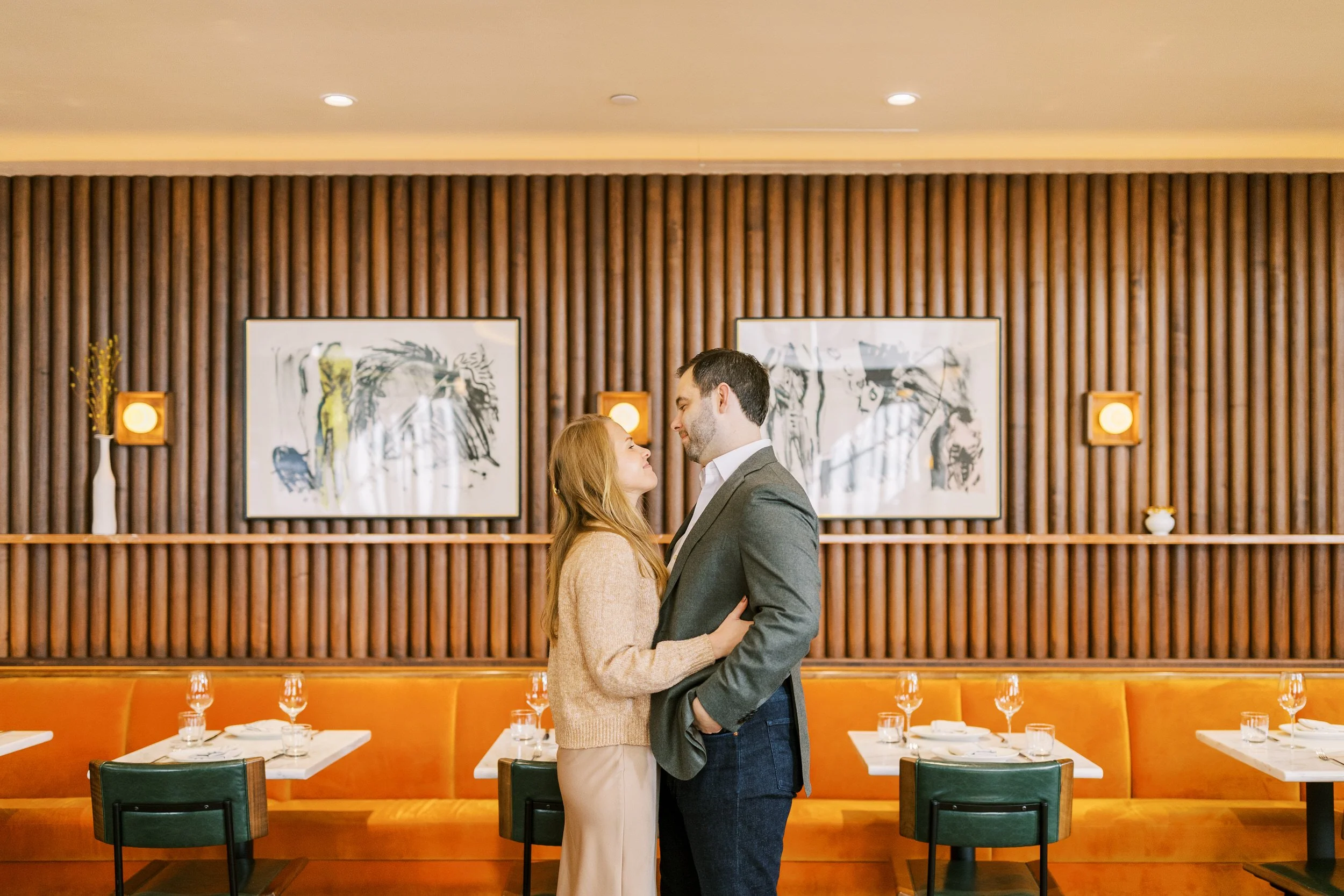 A couple standing in a restaurant with their arms around each other