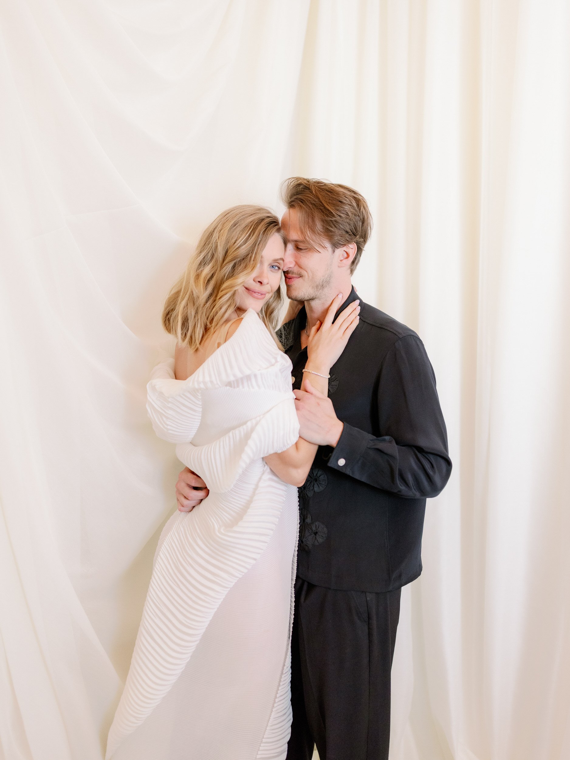 A newlywed couple leaning into each other with their heads resting on each other 