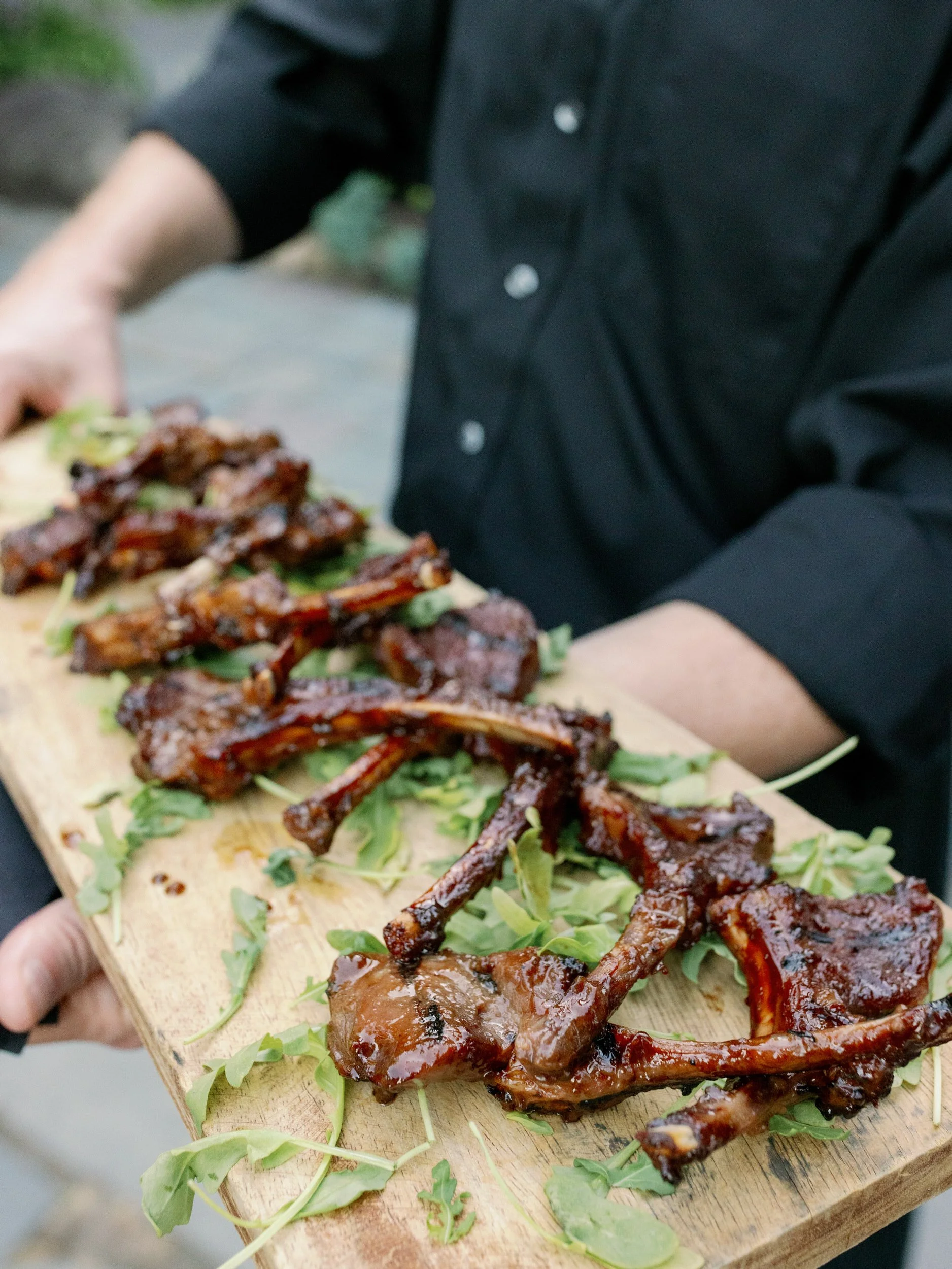 A platter of lamb chops on a wooden plank 