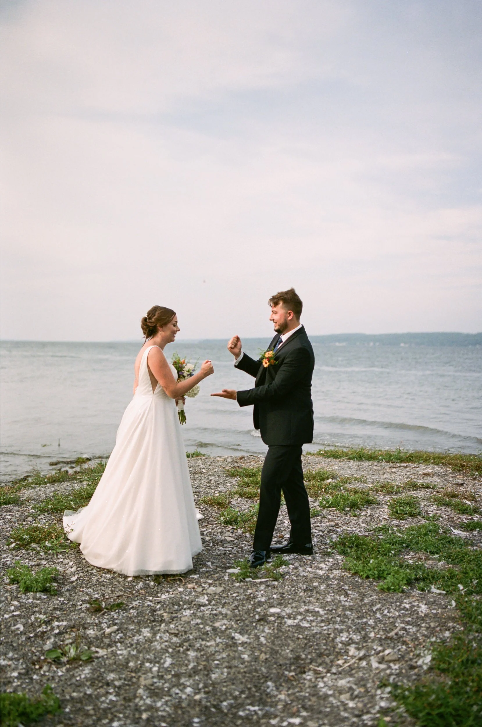 Newlyweds playing rock paper scissors on the edge of the water 