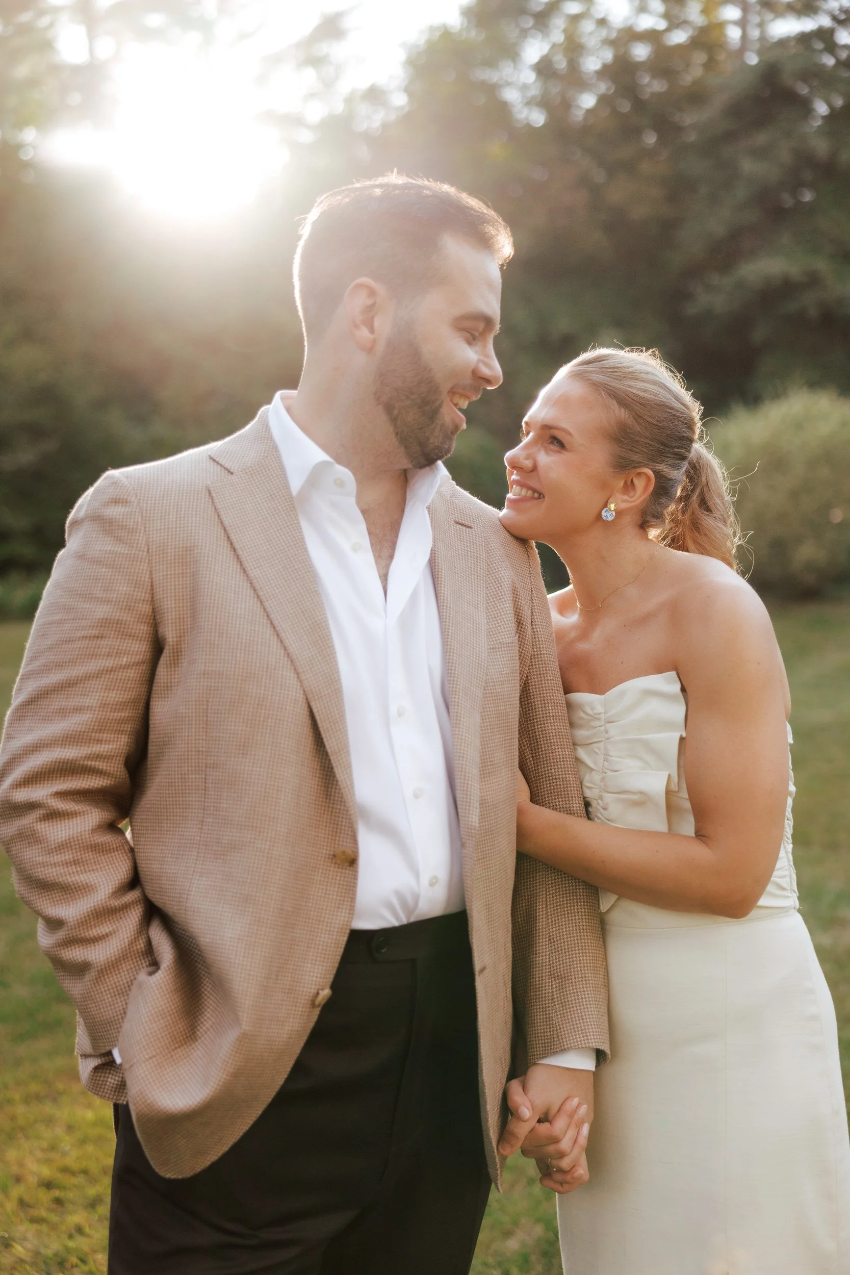 A newlywed couple smiling at each other with their arms linked